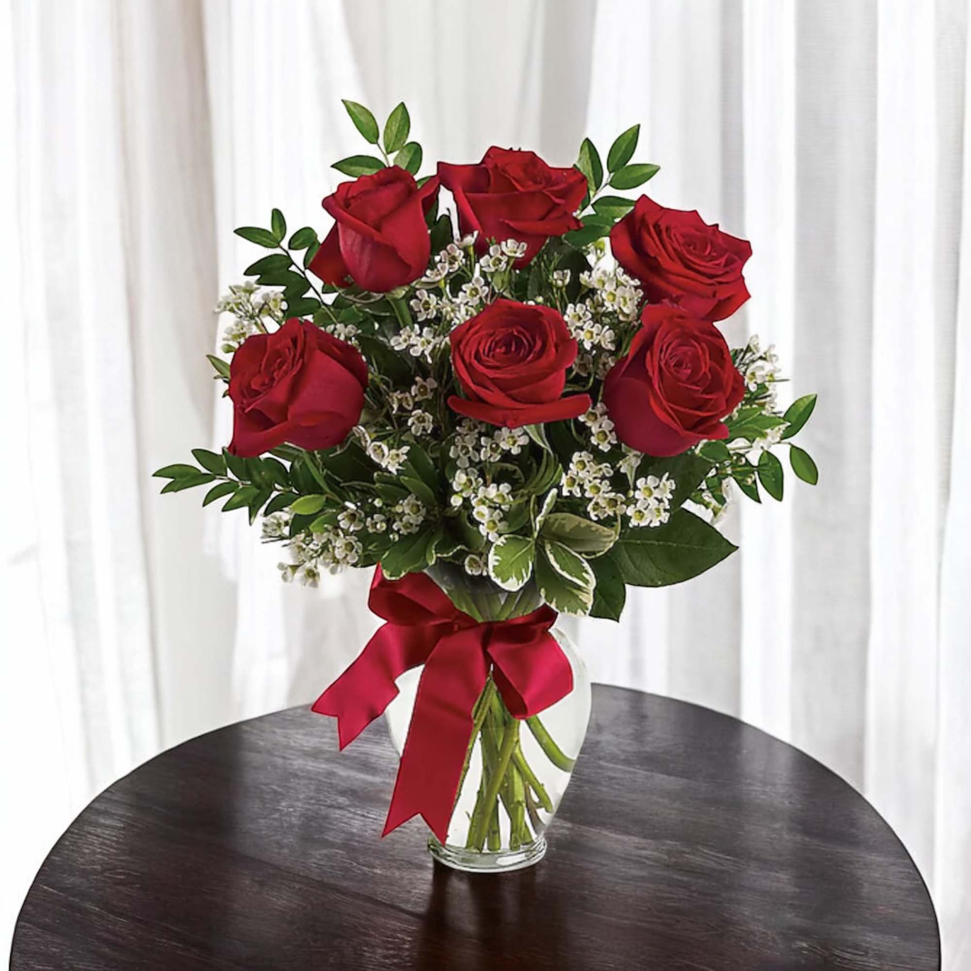 Bouquet of red roses in a clear glass vase with a red ribbon