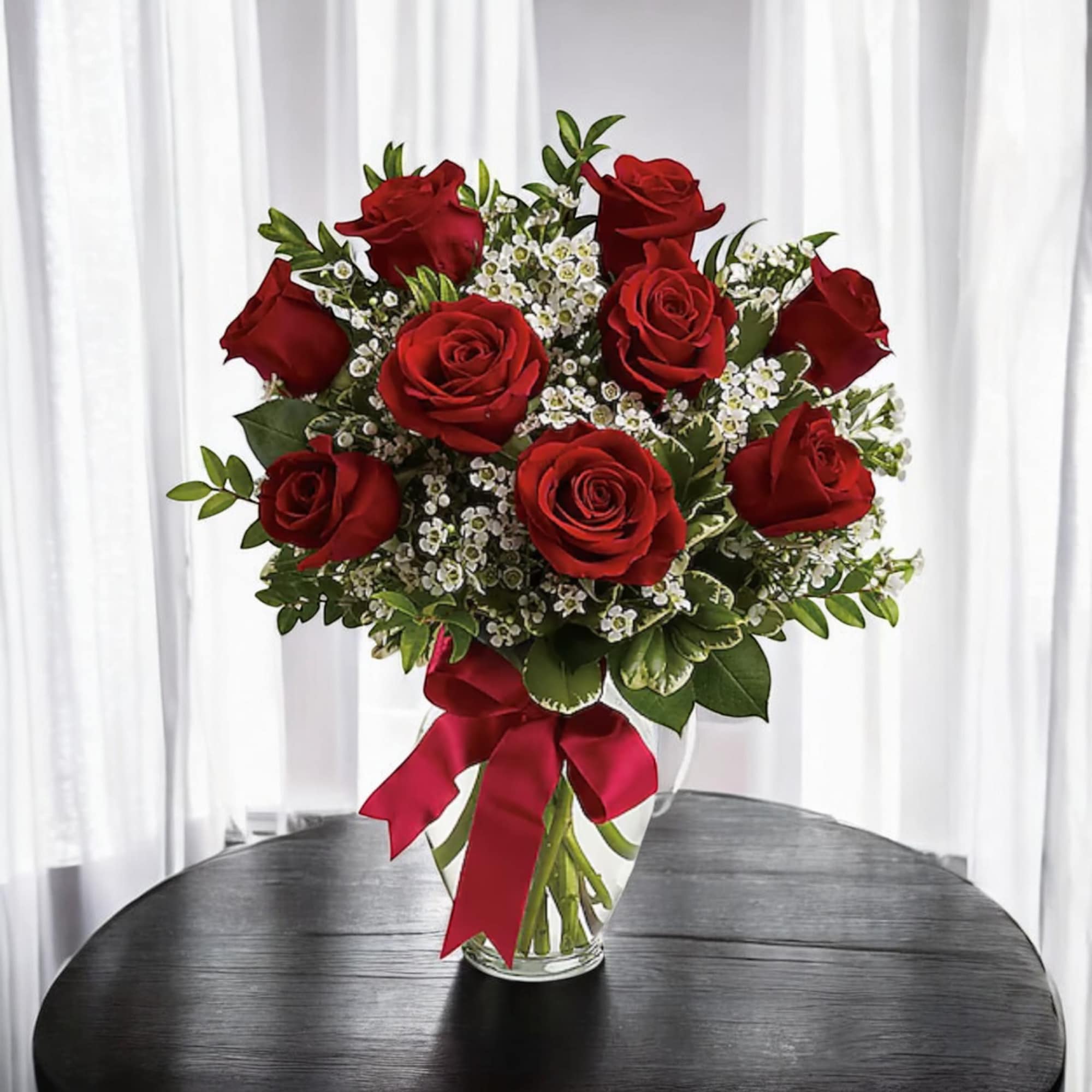Bouquet of red roses with white filler flowers in a clear glass vase