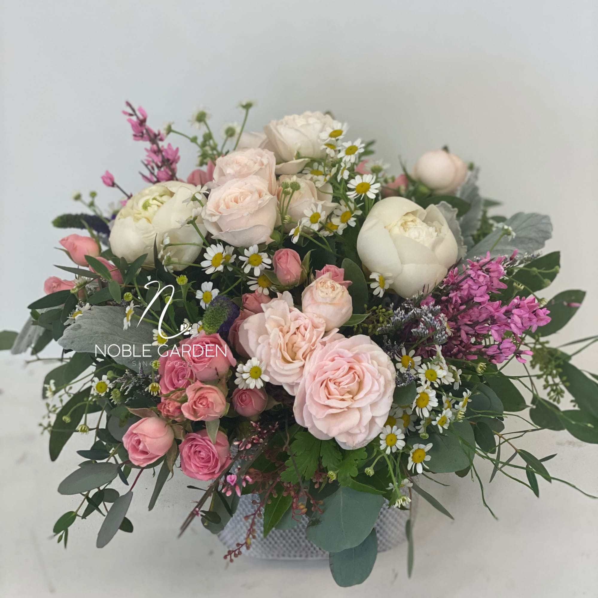 Pink and white rose bouquet with daisies in a low container