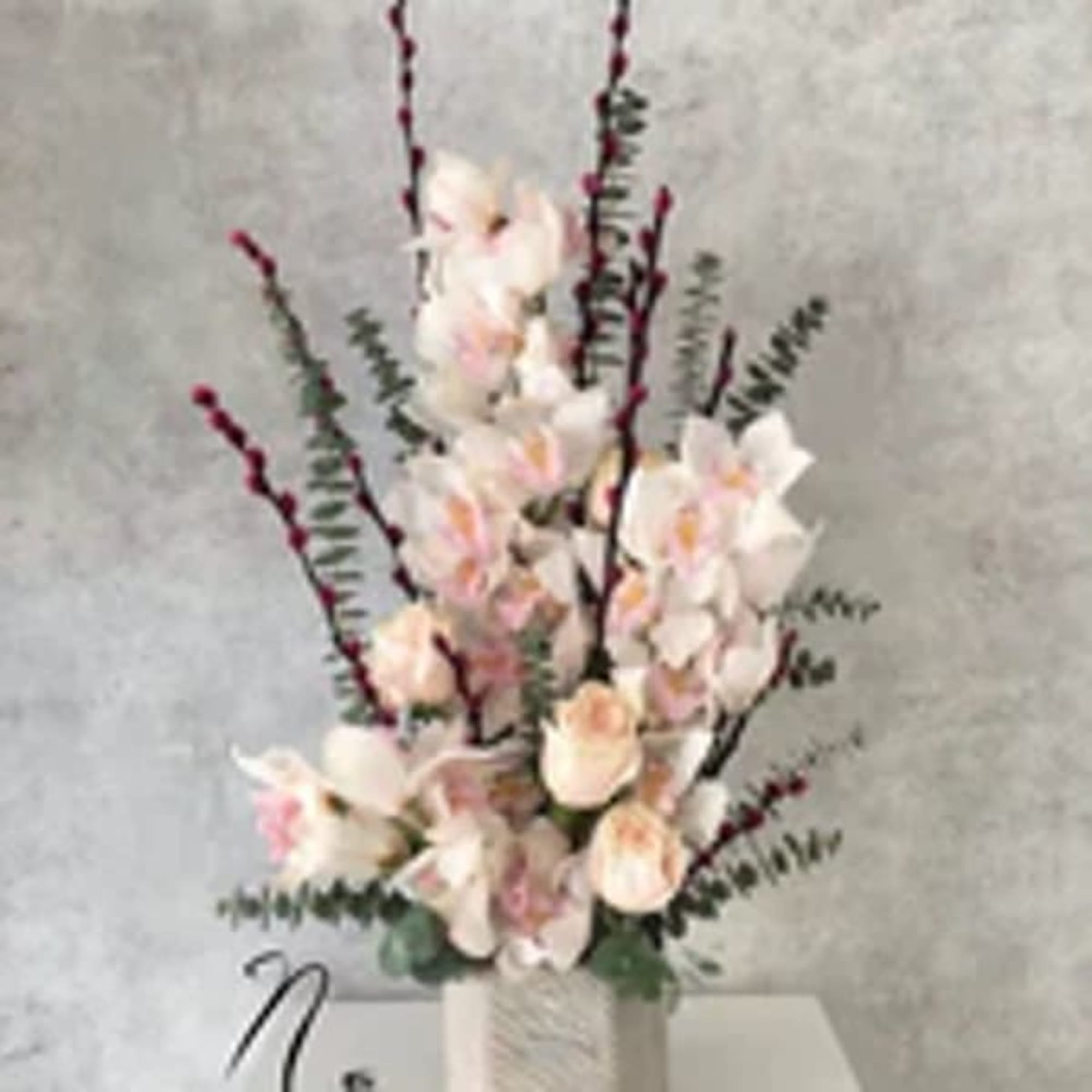 Tall arrangement of pale pink and white flowers in a white vase