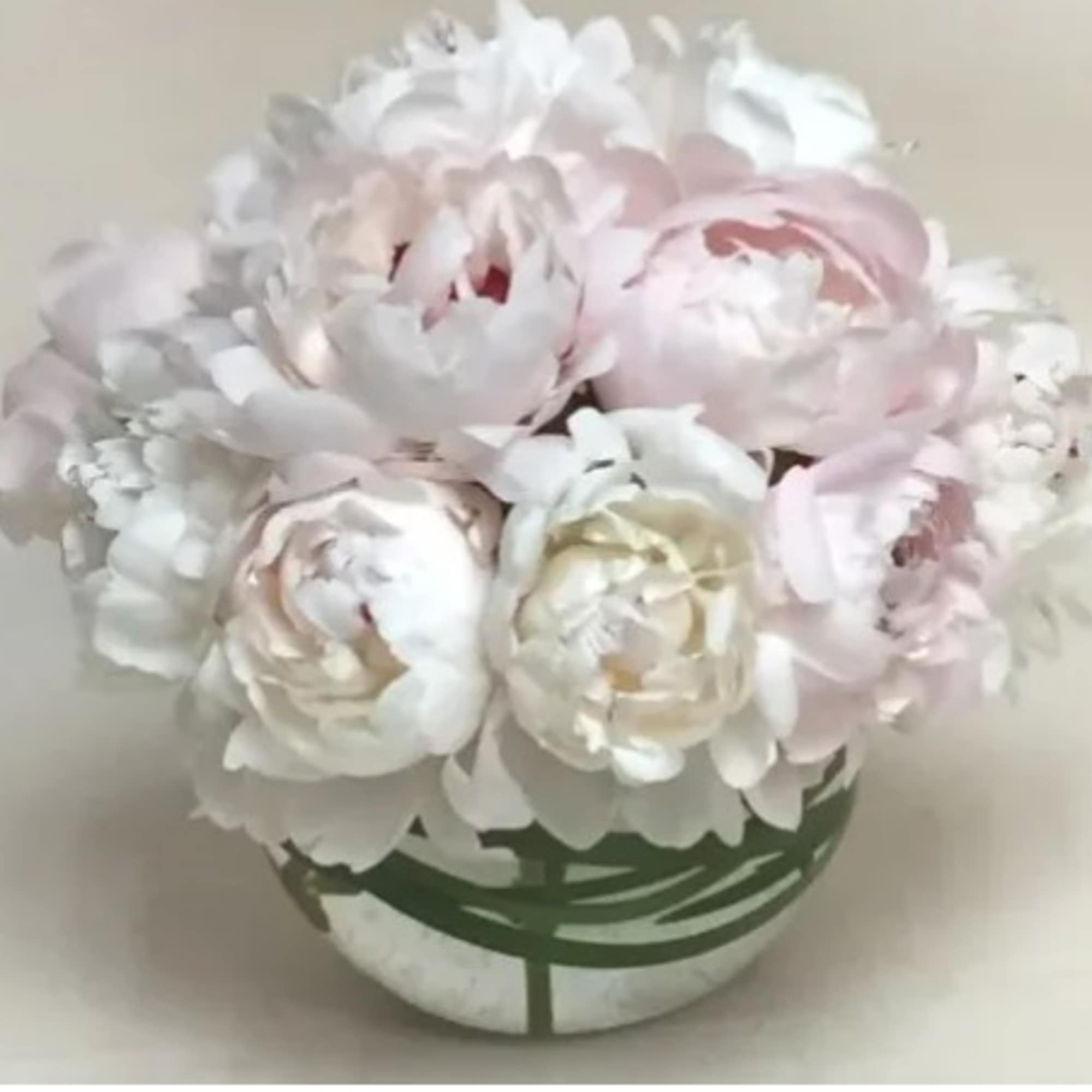 Bouquet of pale pink and white peonies in a round vase
