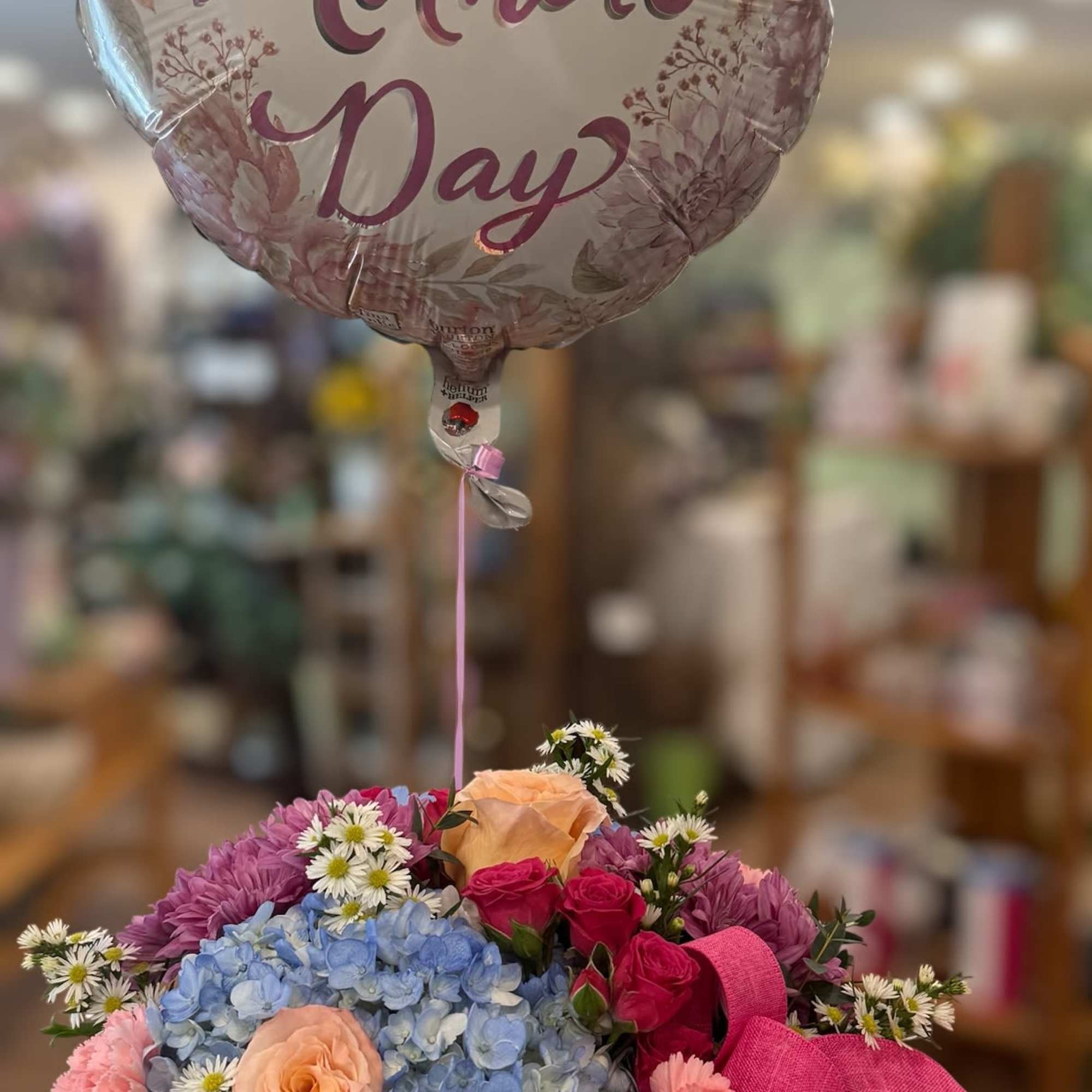 A mix of blue hydrangeas, peach roses, pink spray roses, pink carnations