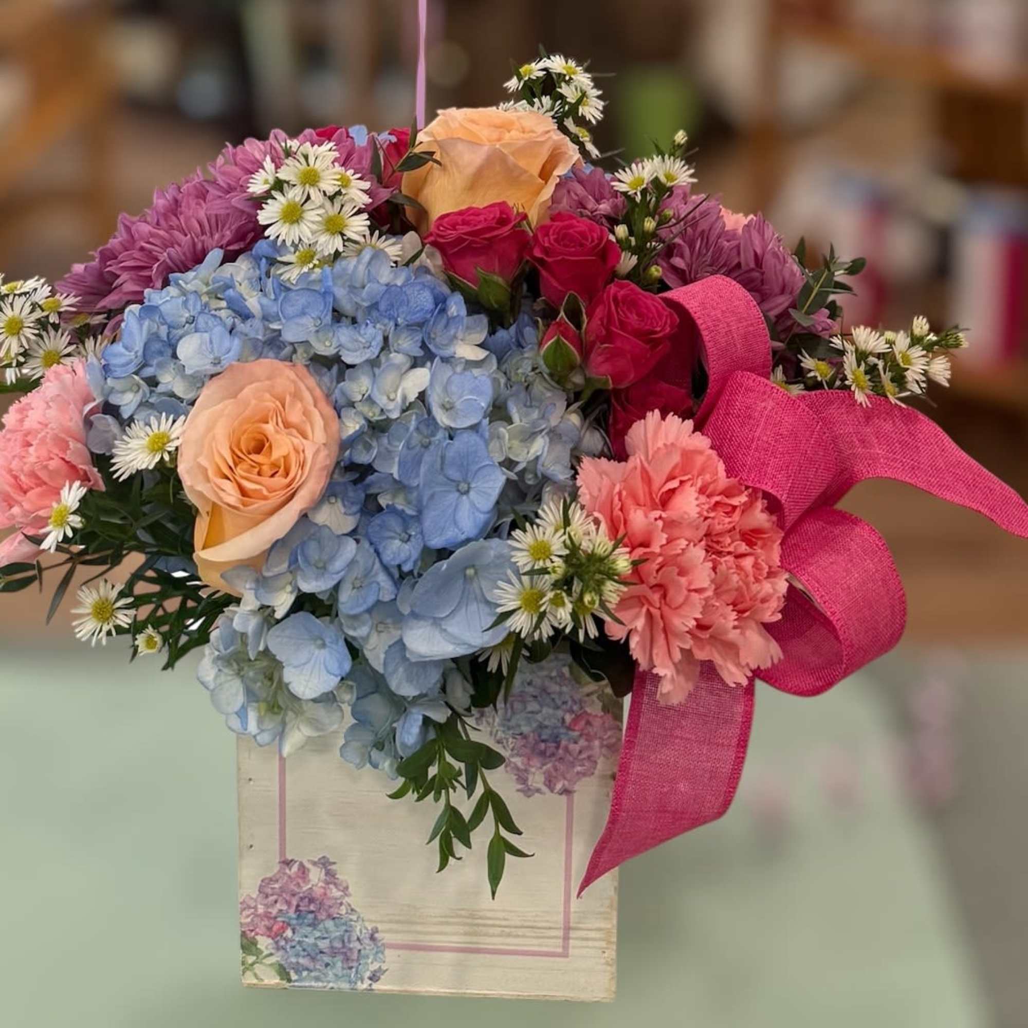 A mix of blue hydrangeas, peach roses, pink spray roses, pink carnations