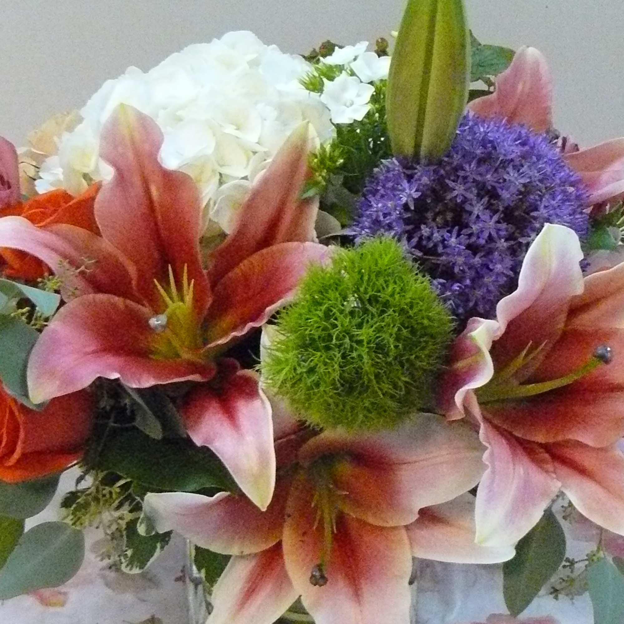 Bouquet of pink lilies, orange roses, and purple flowers