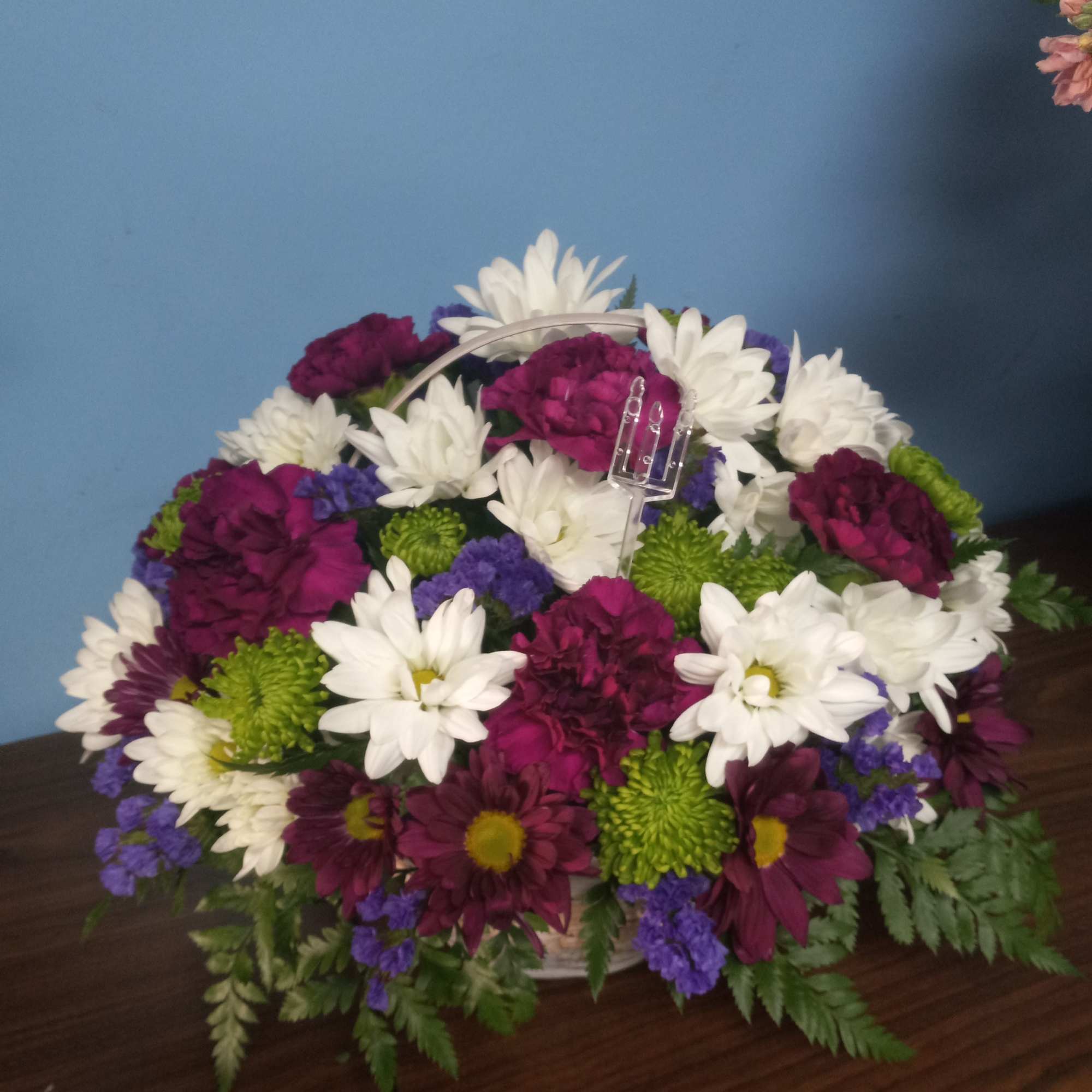 Basket arrangement of white, purple, and magenta daisies with green mums