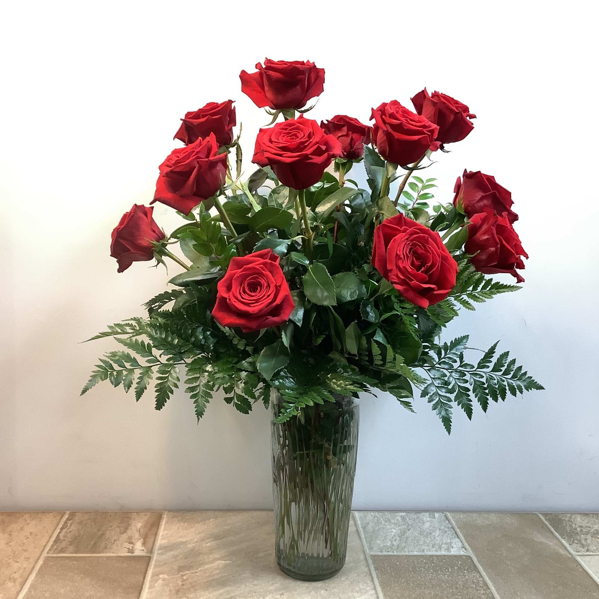 Red roses arranged in a tall glass vase