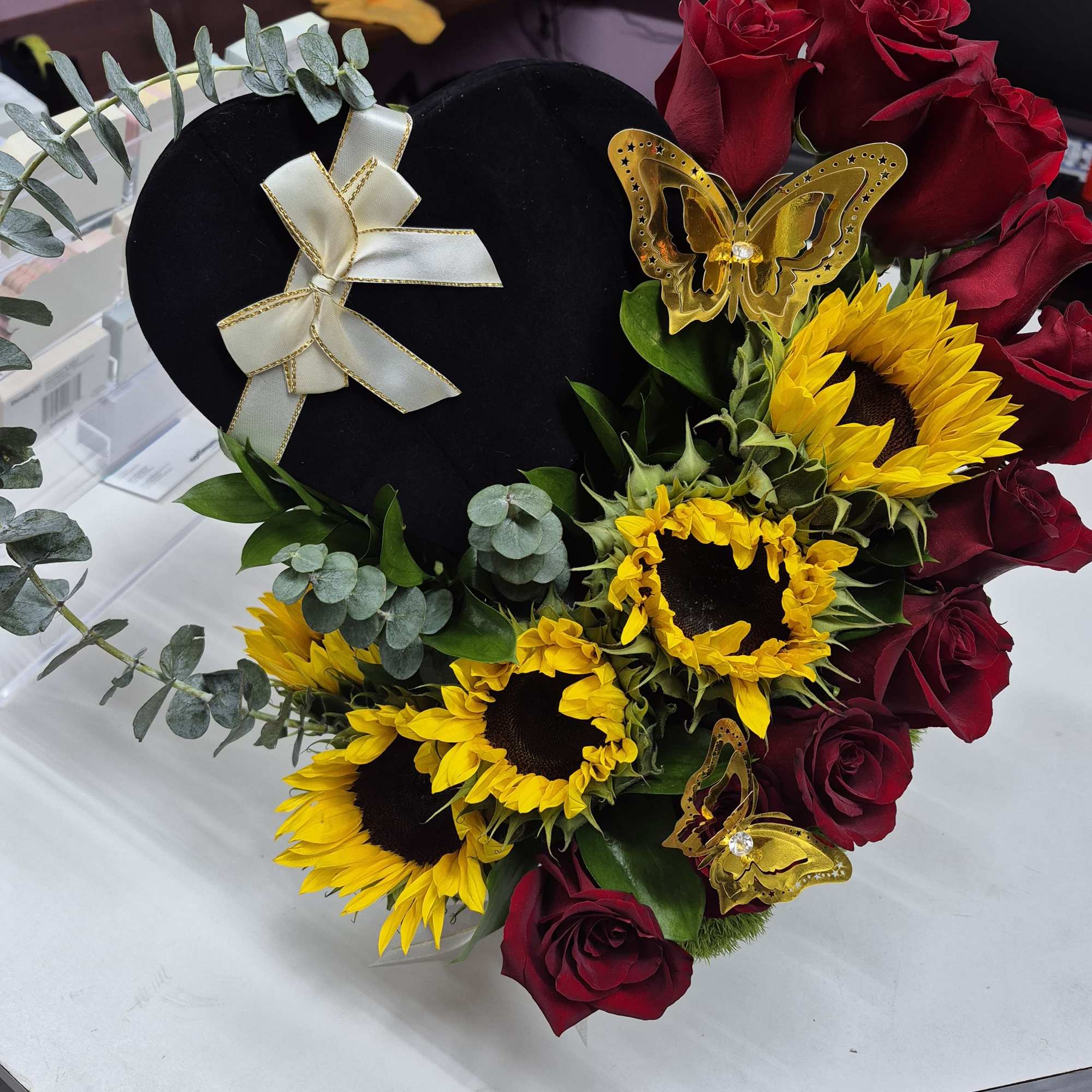 Heart-shaped floral arrangement with red roses and yellow sunflowers