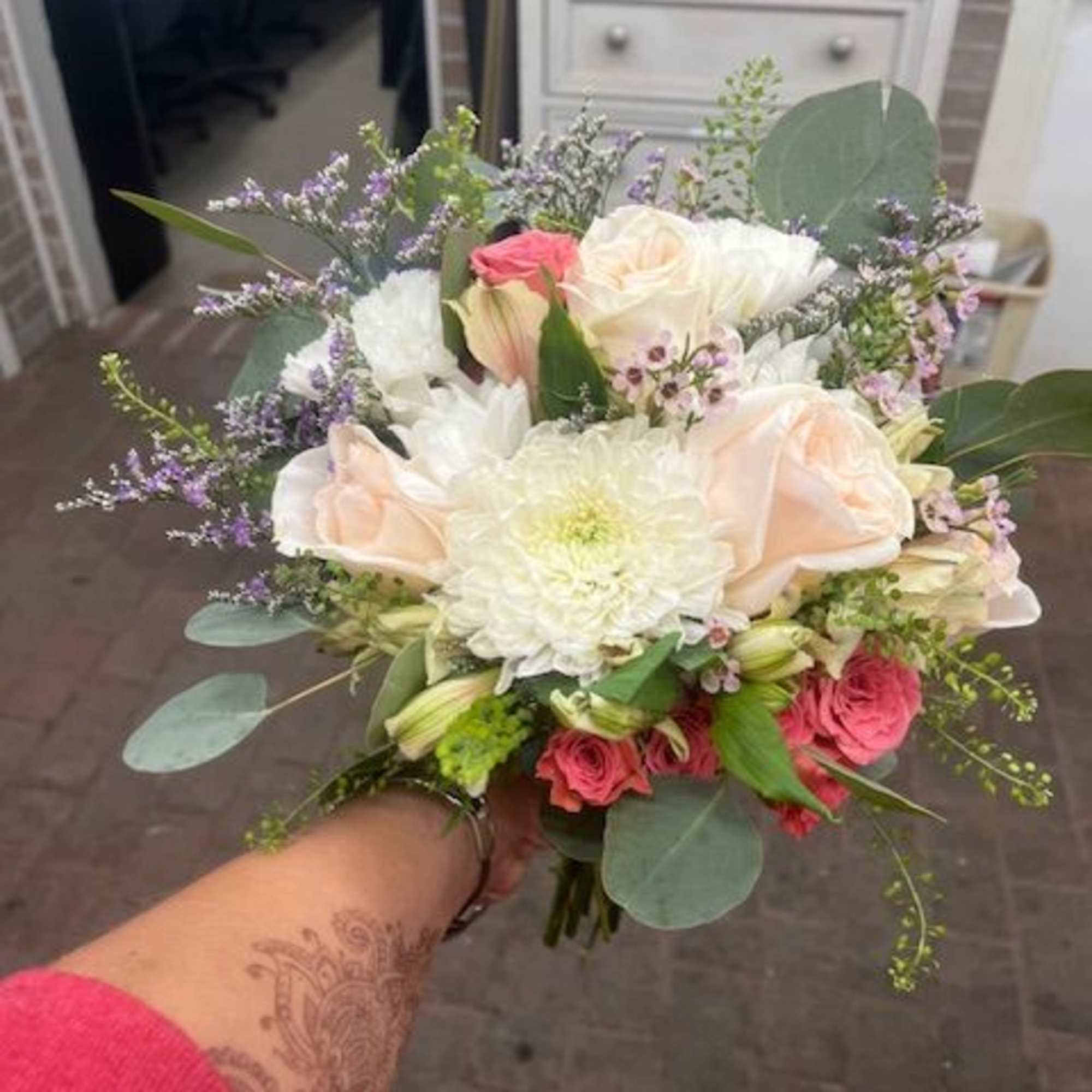 Handheld bouquet of white, blush, and pink flowers with eucalyptus