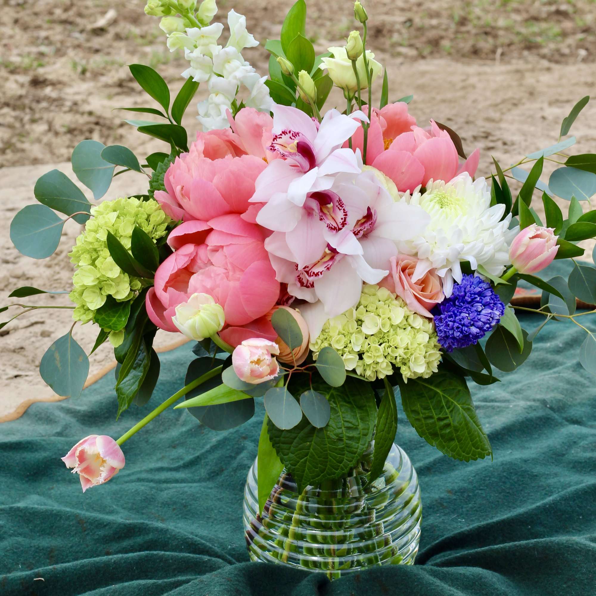 Pink peonies and white orchids in a glass vase with mixed blooms
