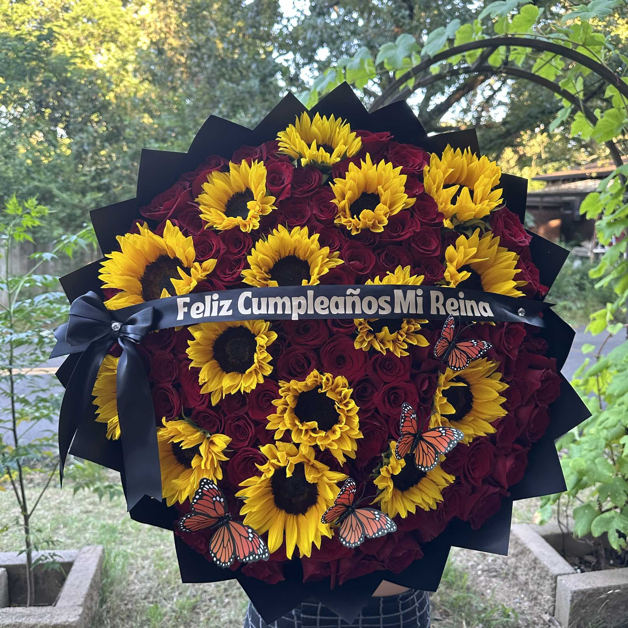 Heart-shaped bouquet of red roses and yellow sunflowers with a birthday ribbon