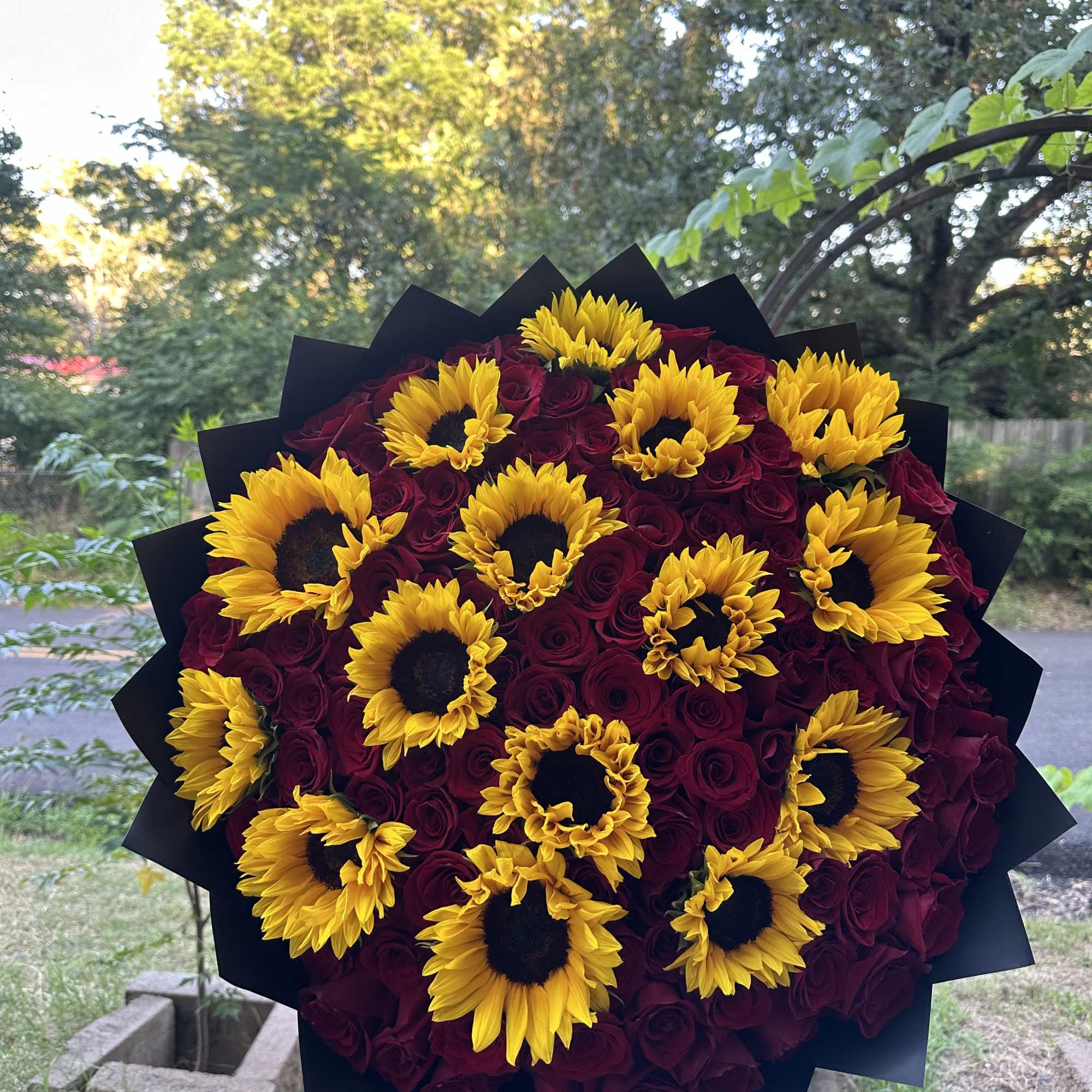 Bouquet of yellow sunflowers and deep red roses wrapped in black paper