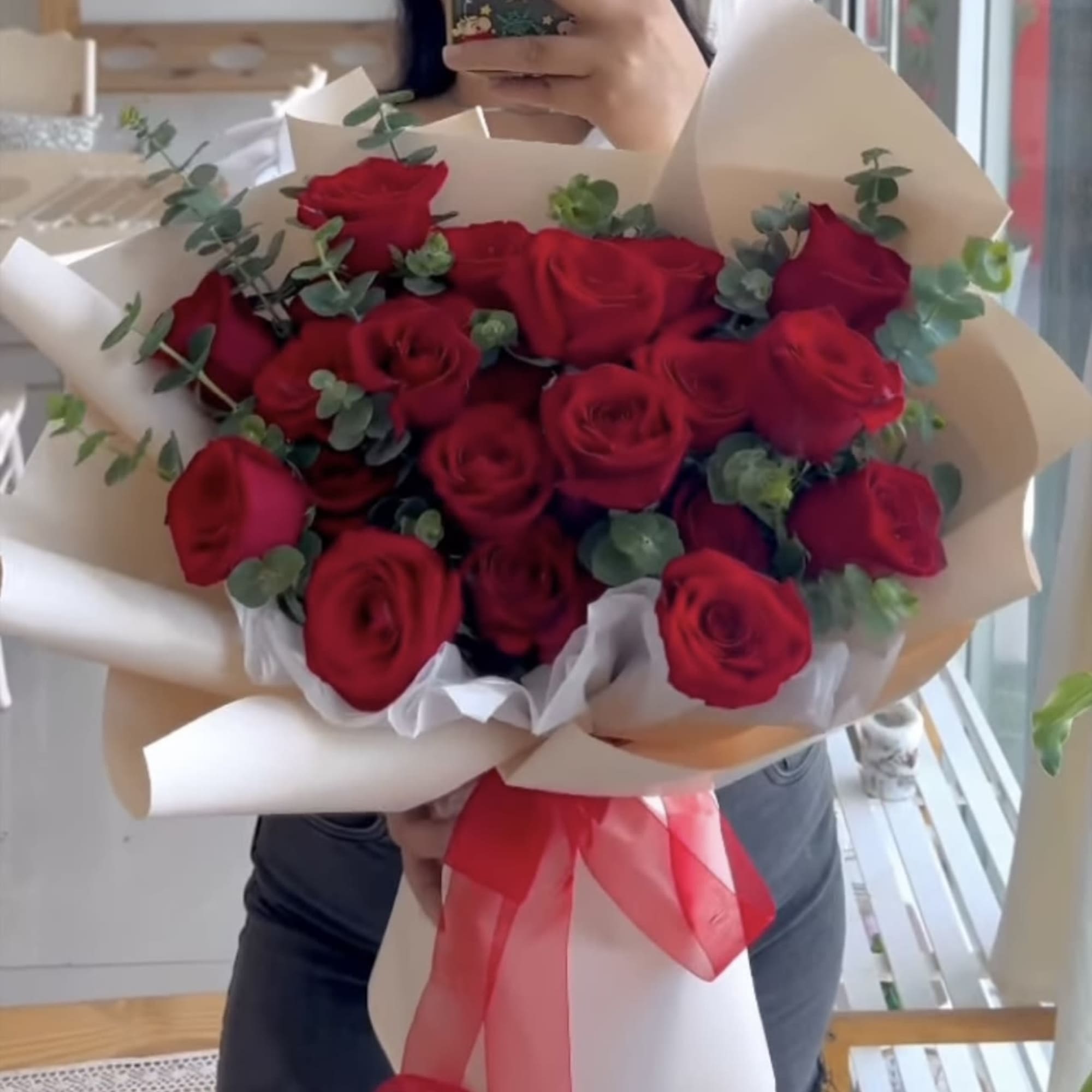 Bouquet of red roses wrapped in cream paper with a red ribbon