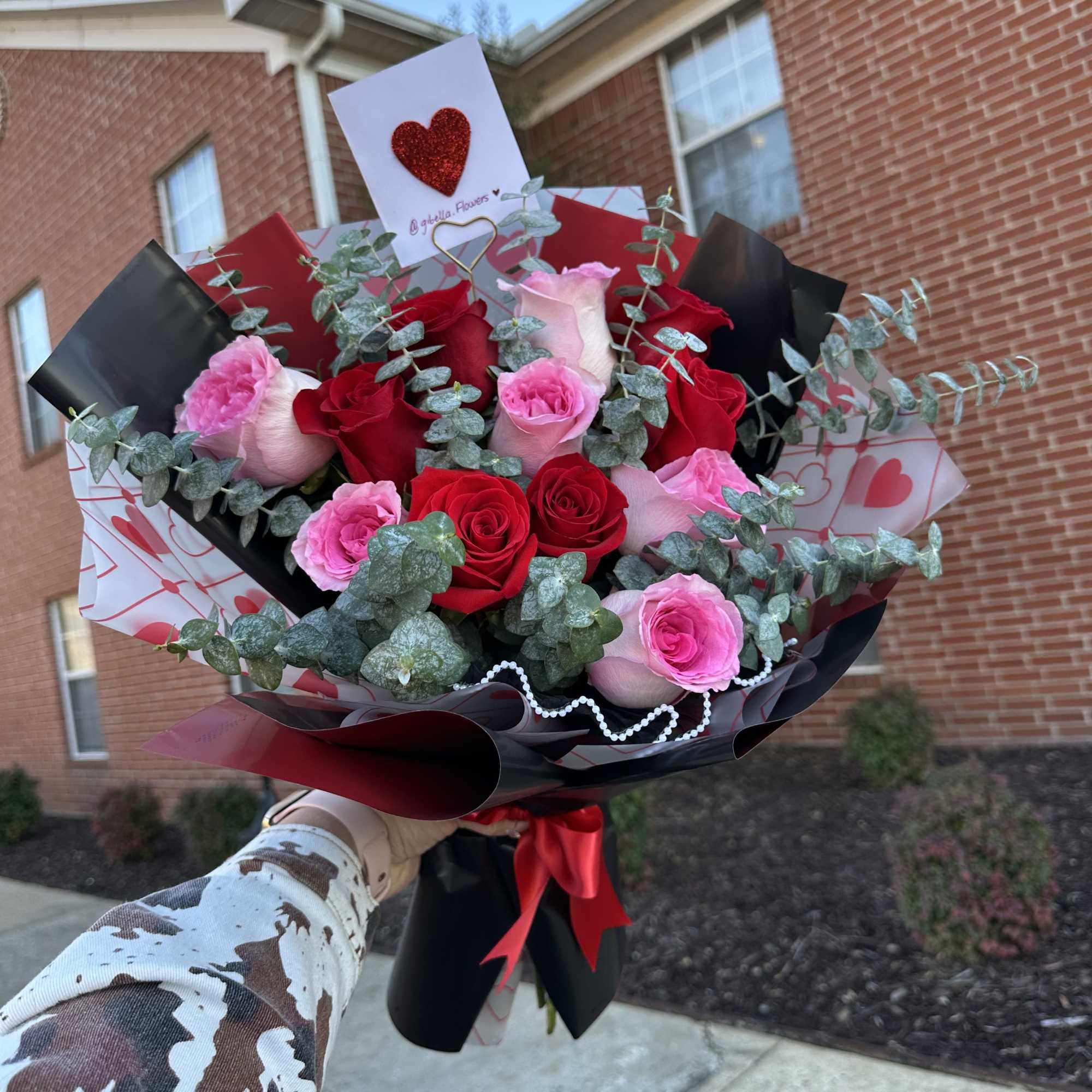 Bouquet of red and pink roses with eucalyptus and heart-themed wrapping