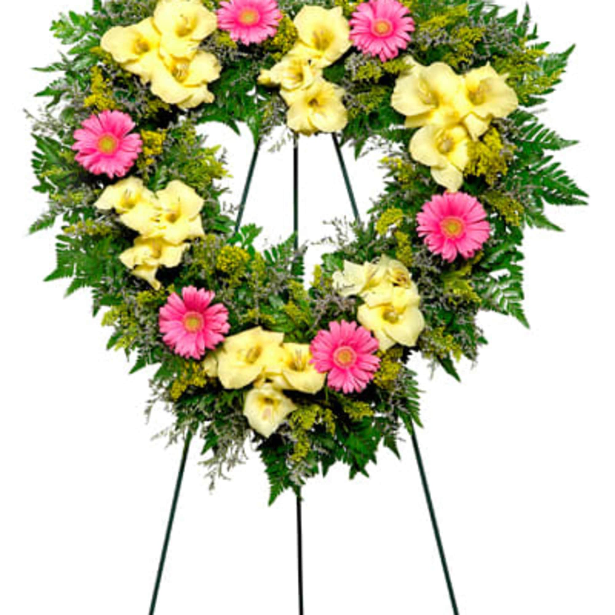 Heart-shaped floral wreath with yellow calla lilies and pink daisies on a stand