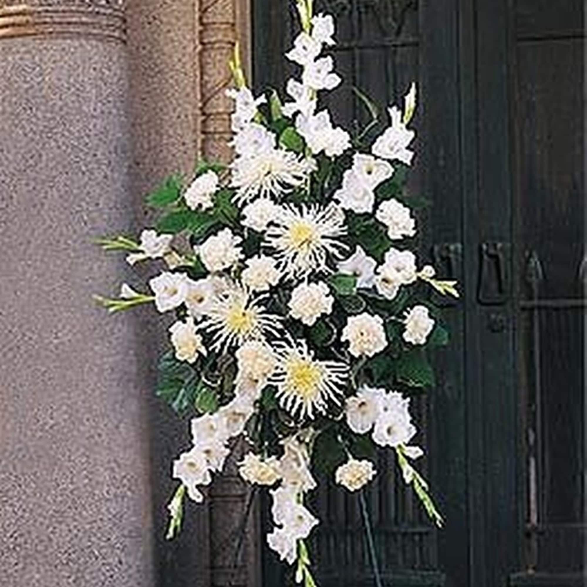 Standing spray of white gladiolus, carnations, and spider mums on an easel.