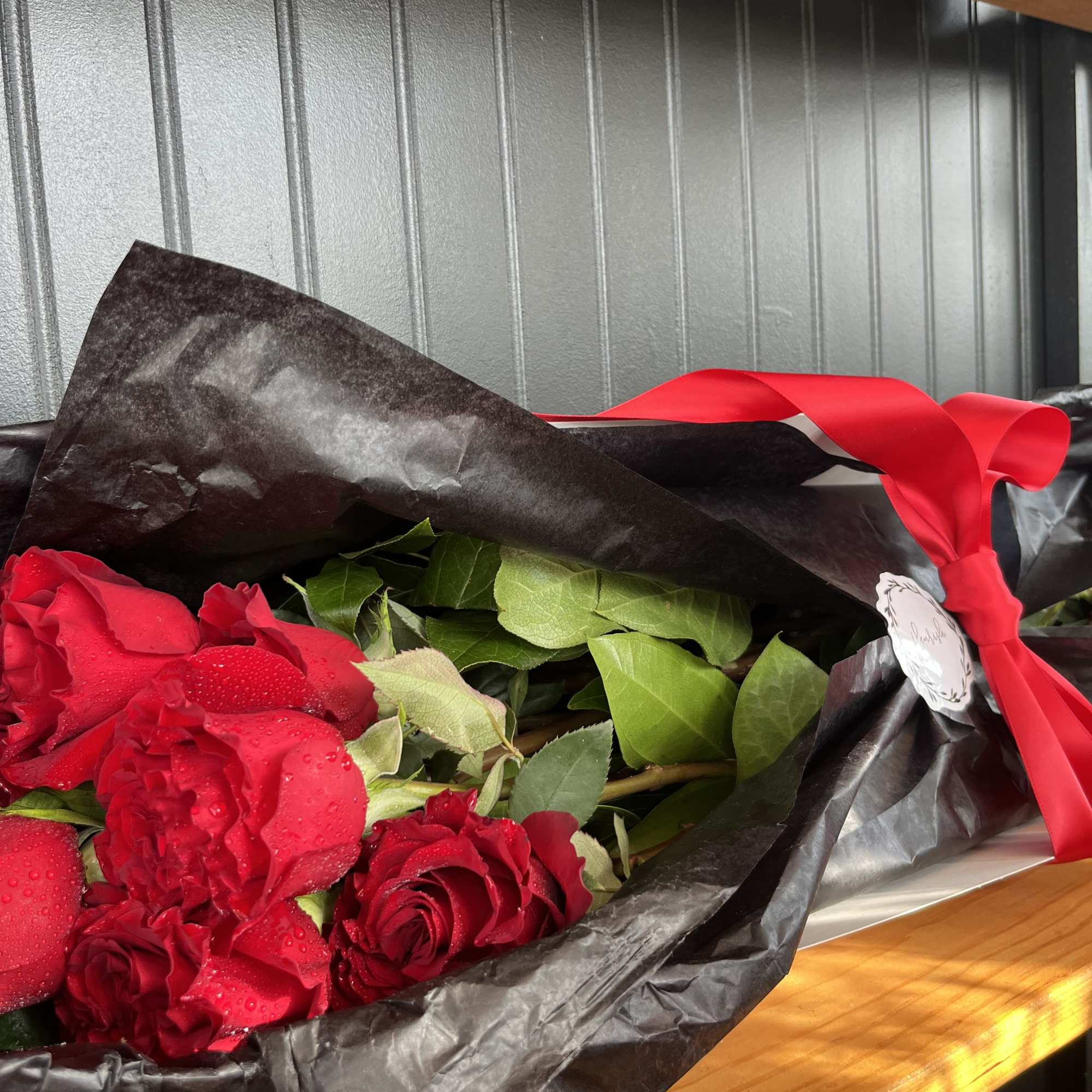 Bouquet of red roses wrapped in black paper with a red ribbon