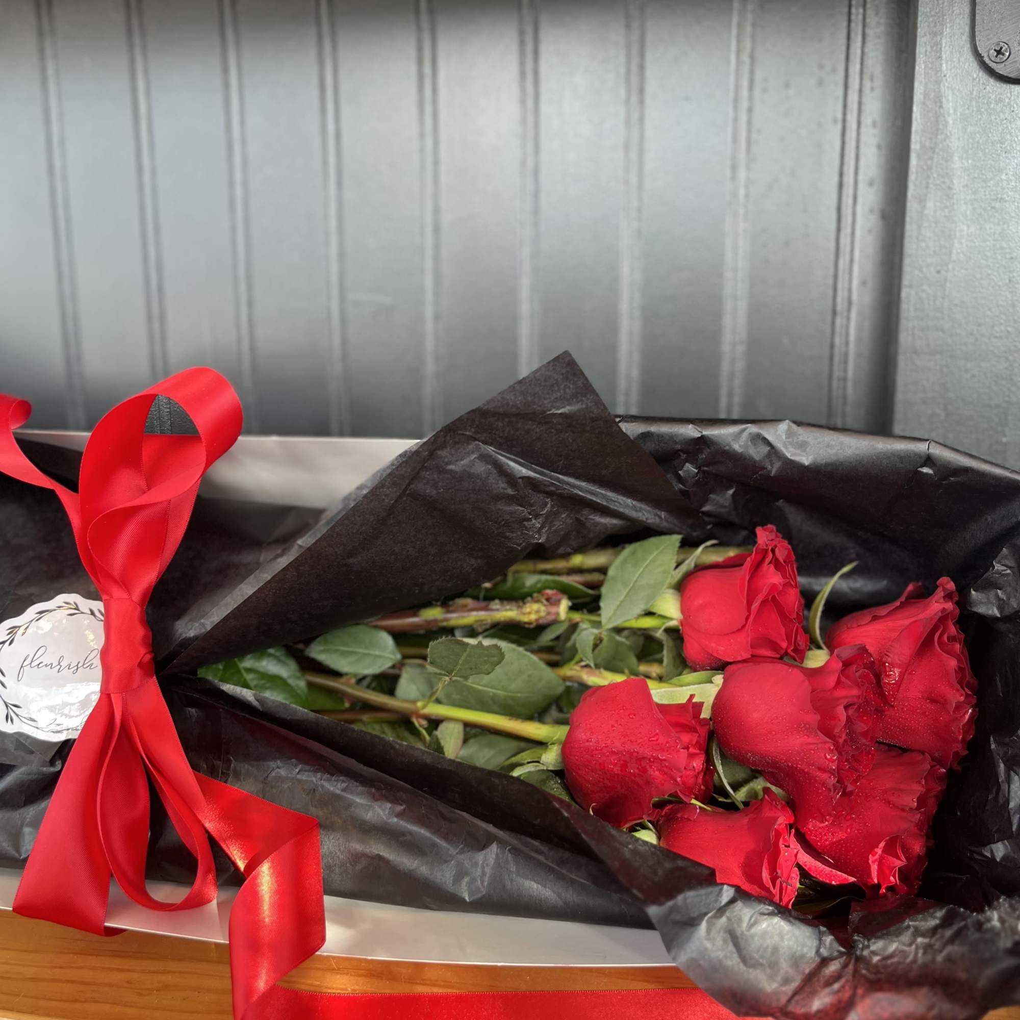 Bouquet of red roses wrapped in black paper with a red ribbon