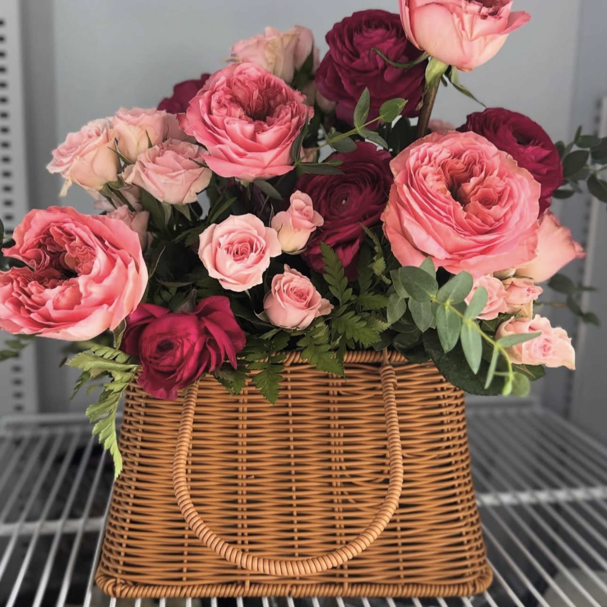 Pink and burgundy roses arranged in a wicker basket
