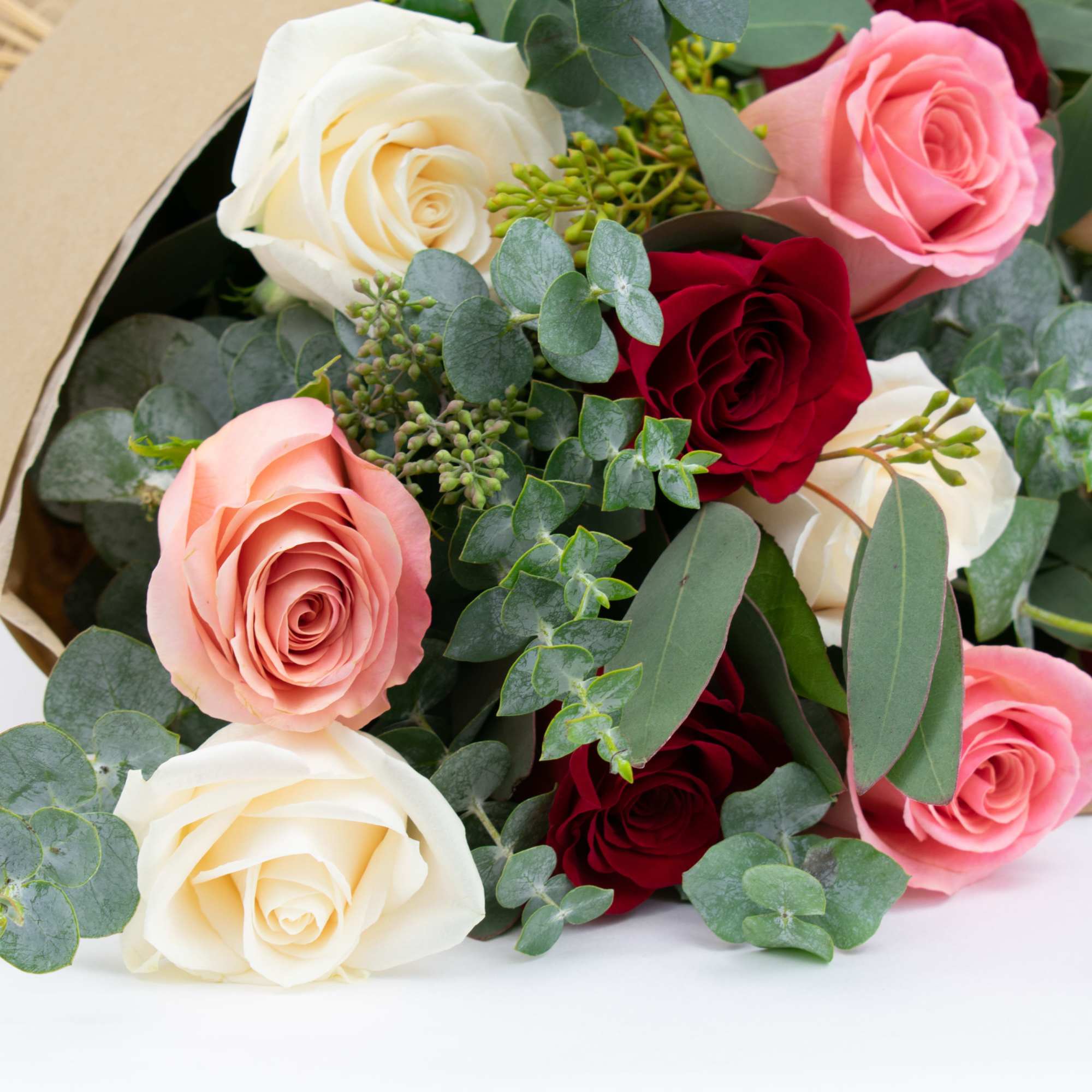 Bouquet of pink, white, and red roses with eucalyptus wrapping