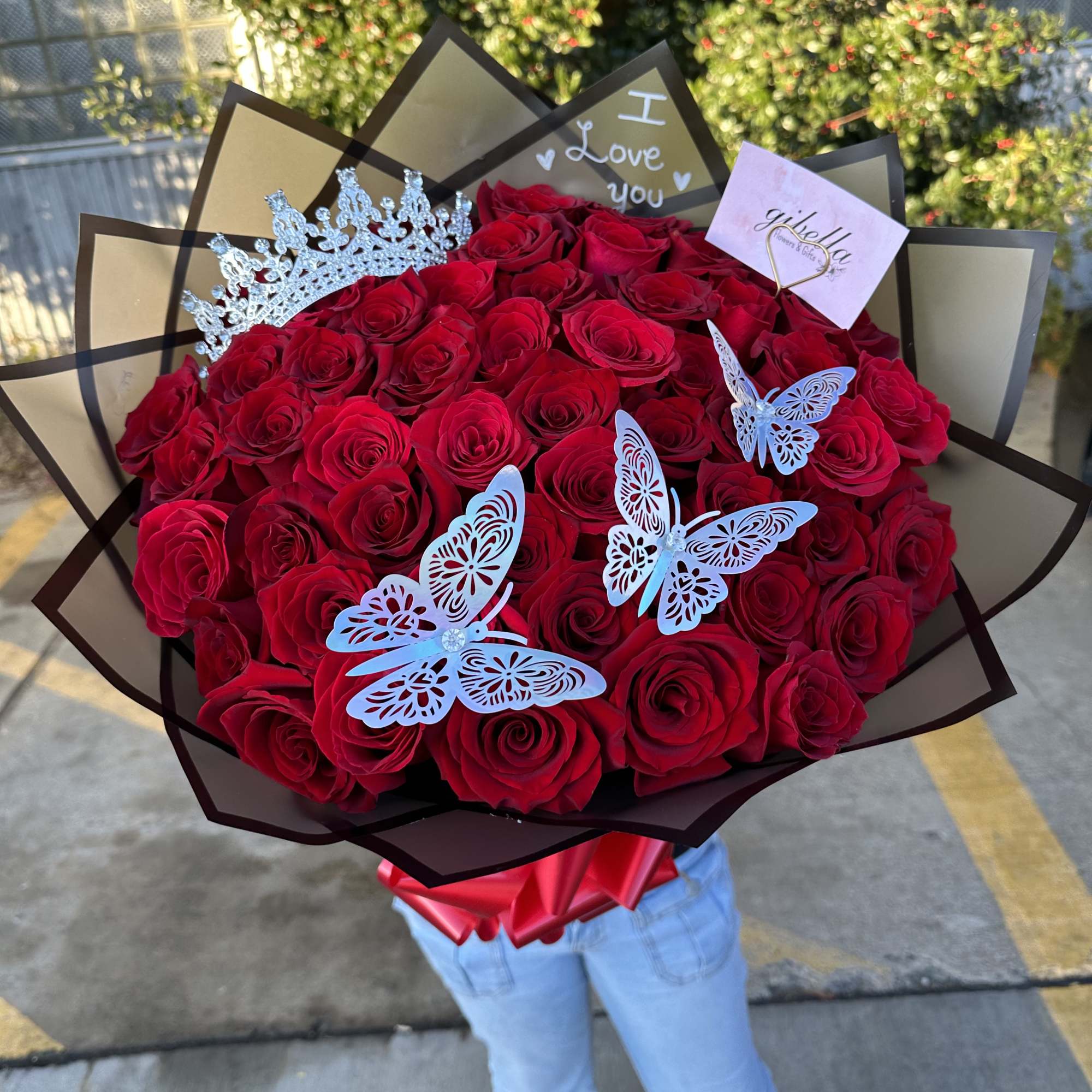 Large bouquet of red roses with butterfly decorations and a crown topper