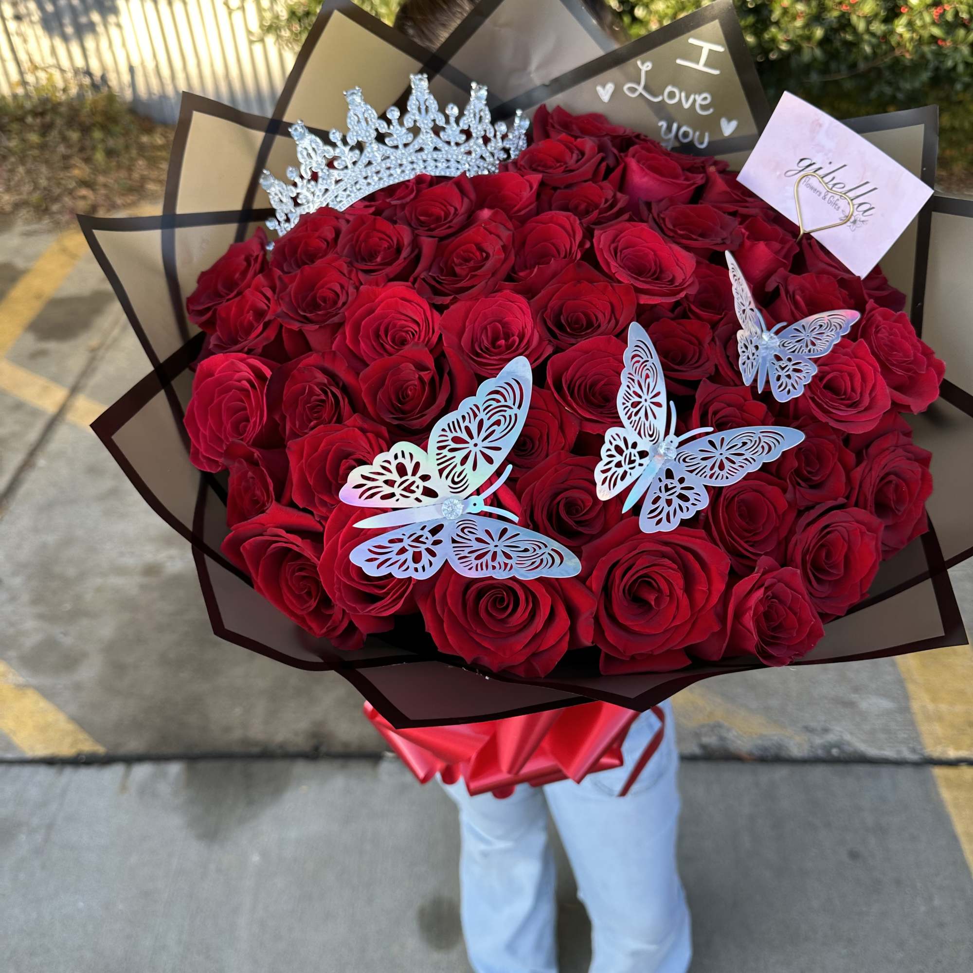 Large bouquet of red roses with butterfly decorations and a crown topper