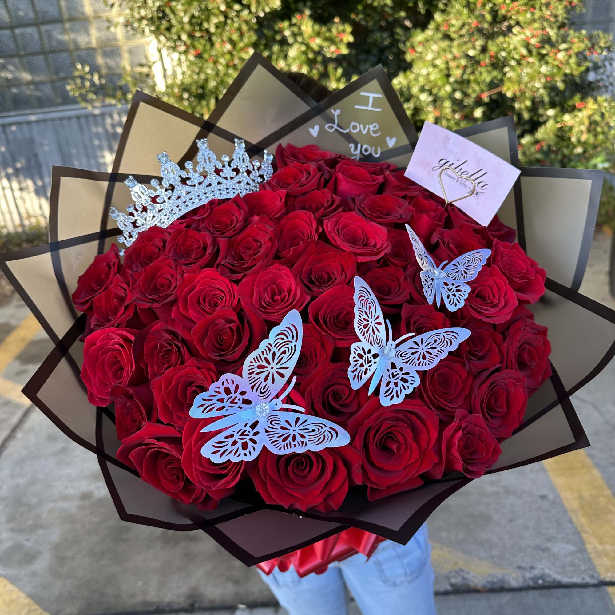 Large bouquet of red roses with butterfly decorations and a tiara topper