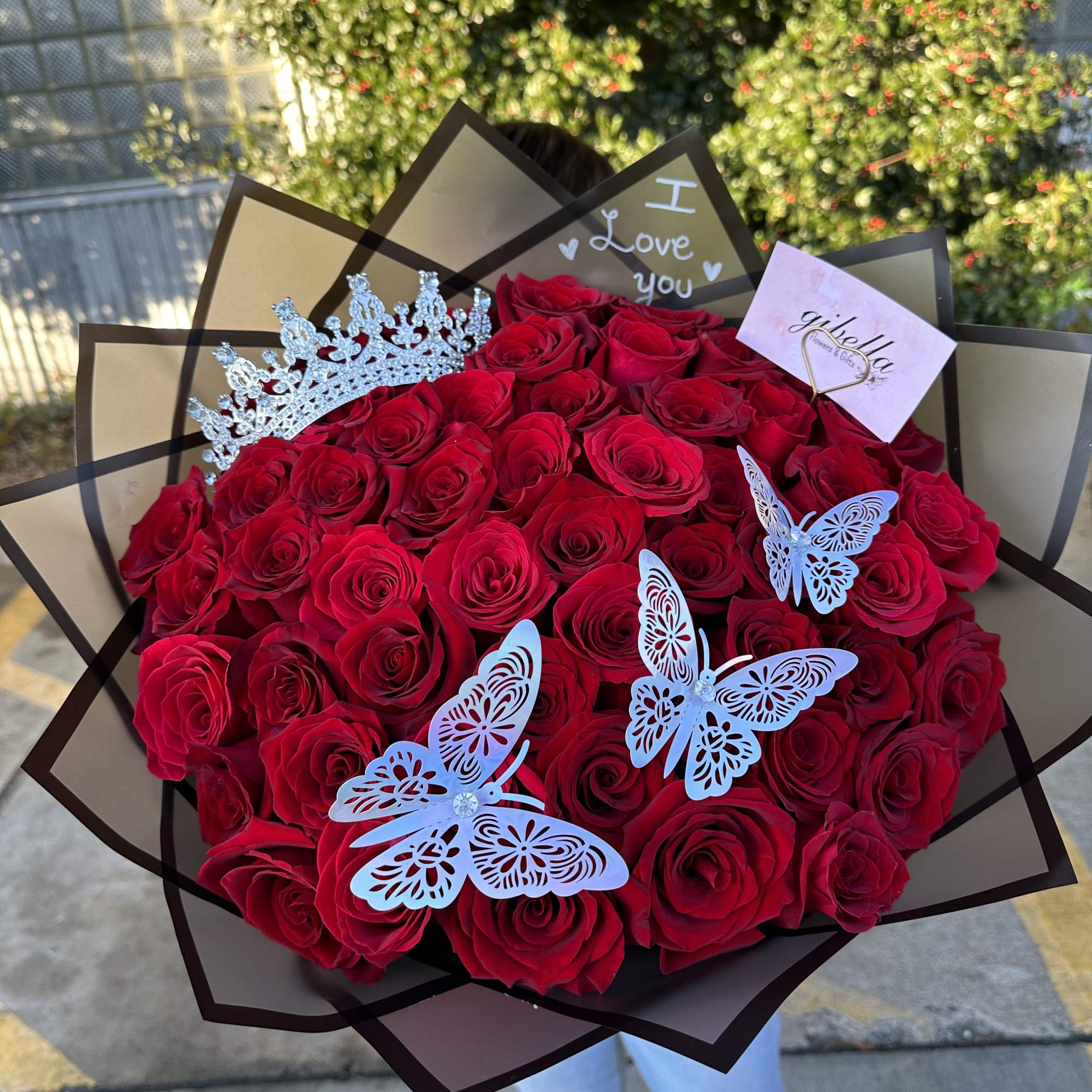 Large bouquet of red roses with butterfly decorations and a crown topper