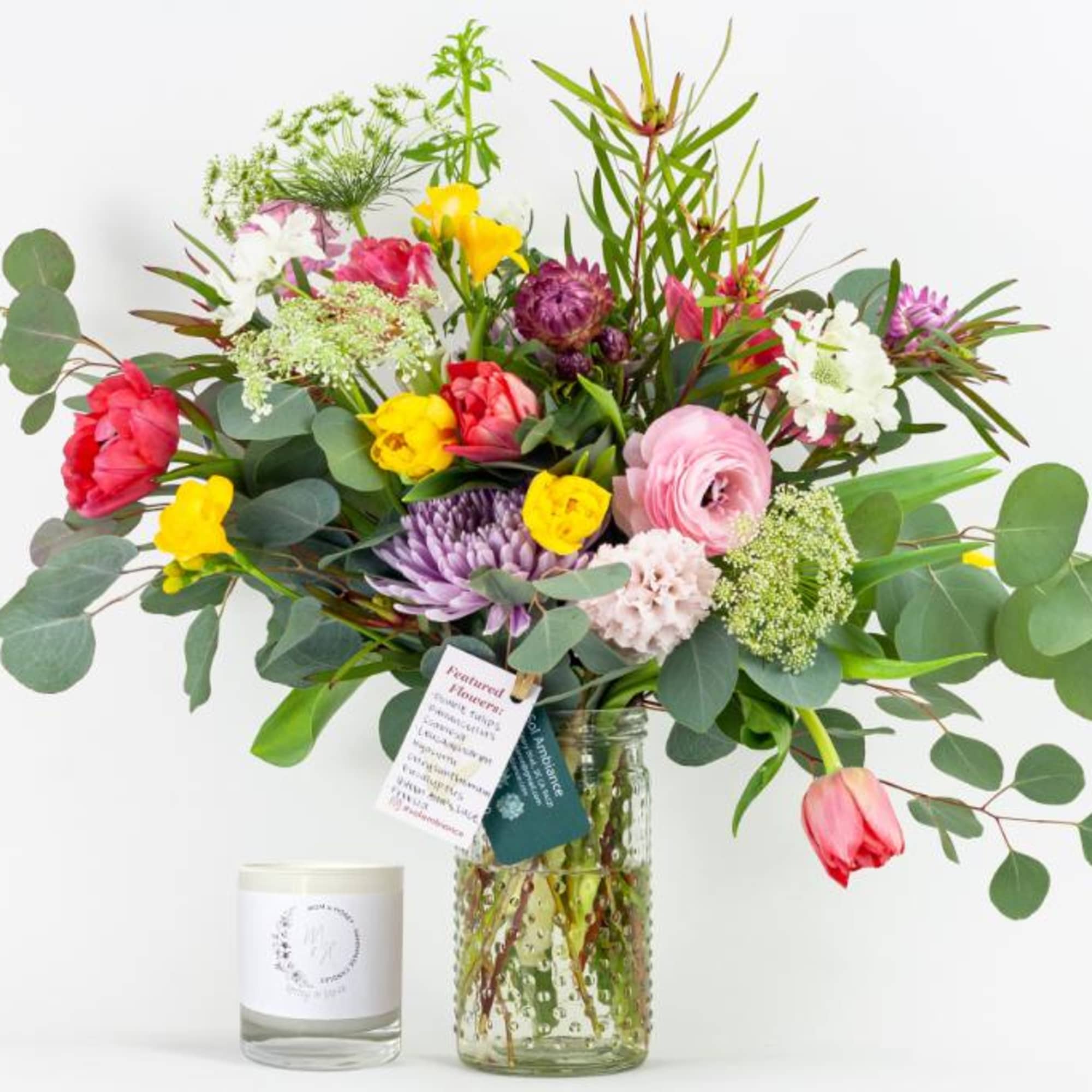 Mixed bouquet in a glass vase with a candle beside it