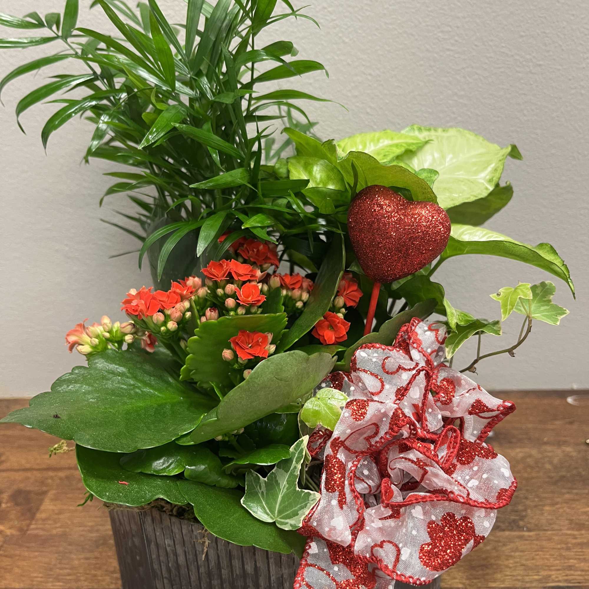 Potted plant arrangement with red flowers and a glittery heart pick