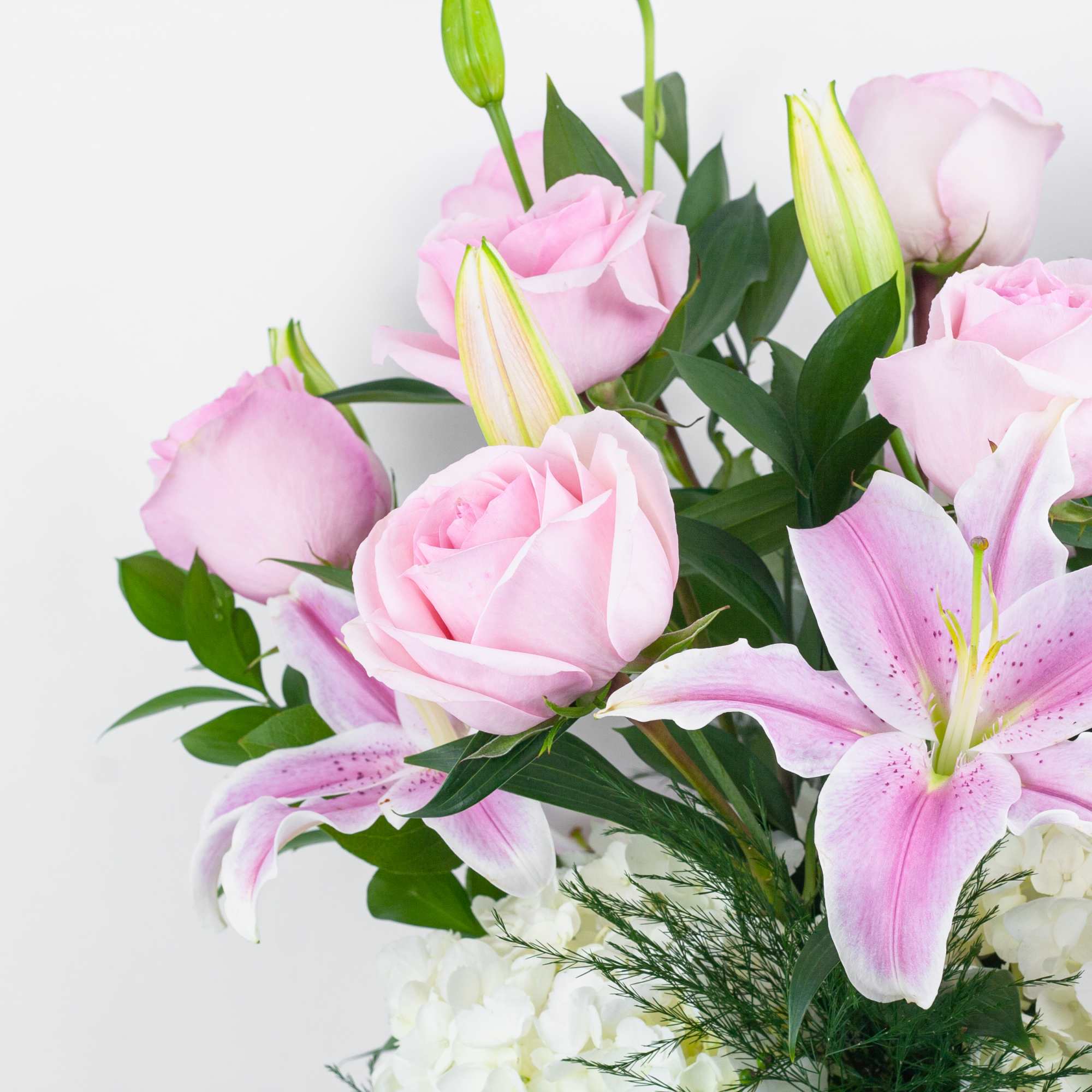 Pink roses and lilies arranged with white hydrangeas