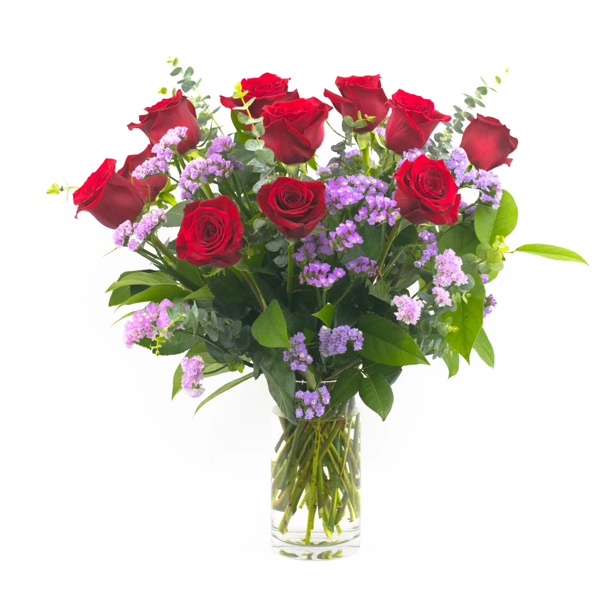 Red roses and purple filler flowers in a clear glass vase