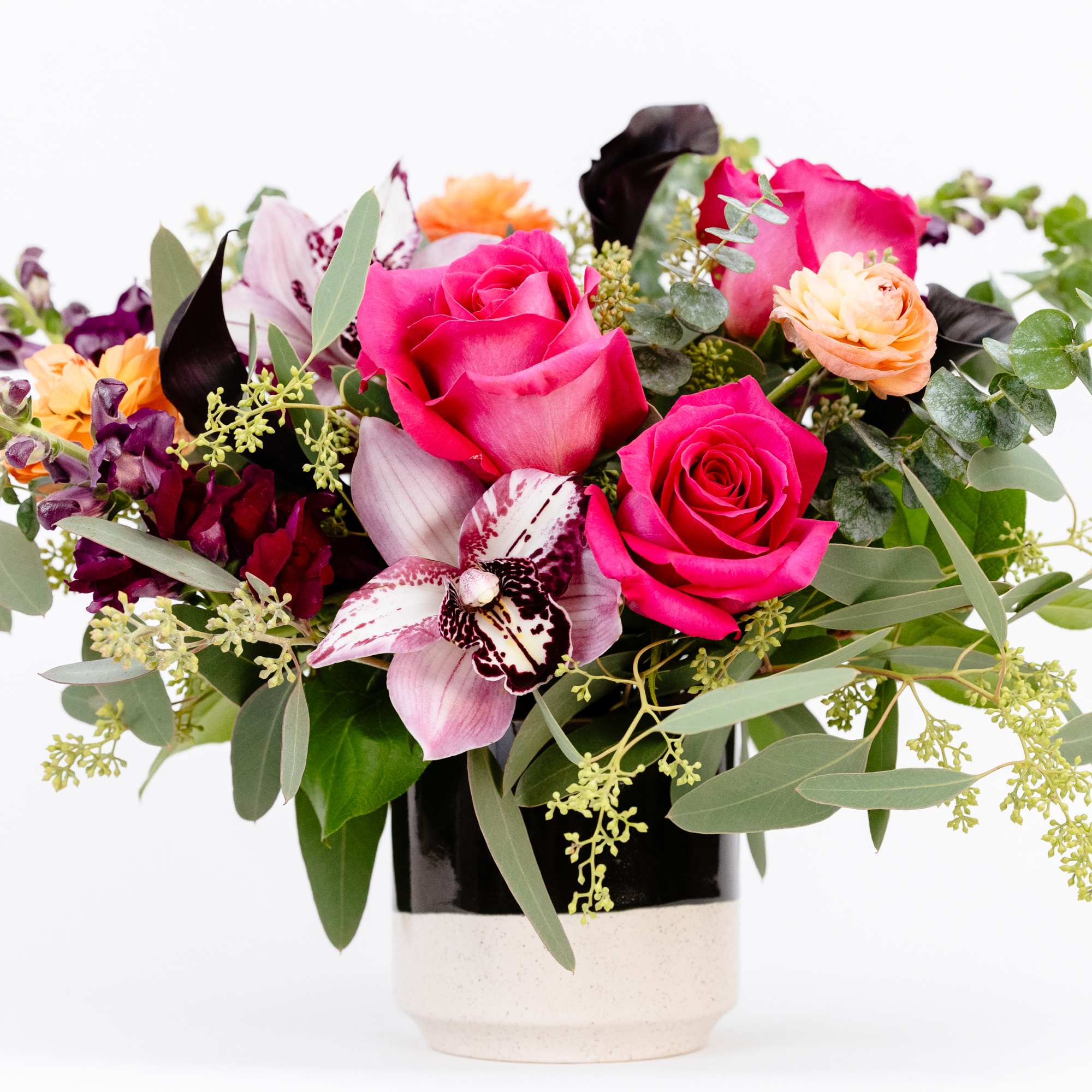 Mixed bouquet of pink roses and orchids in a black-and-white vase