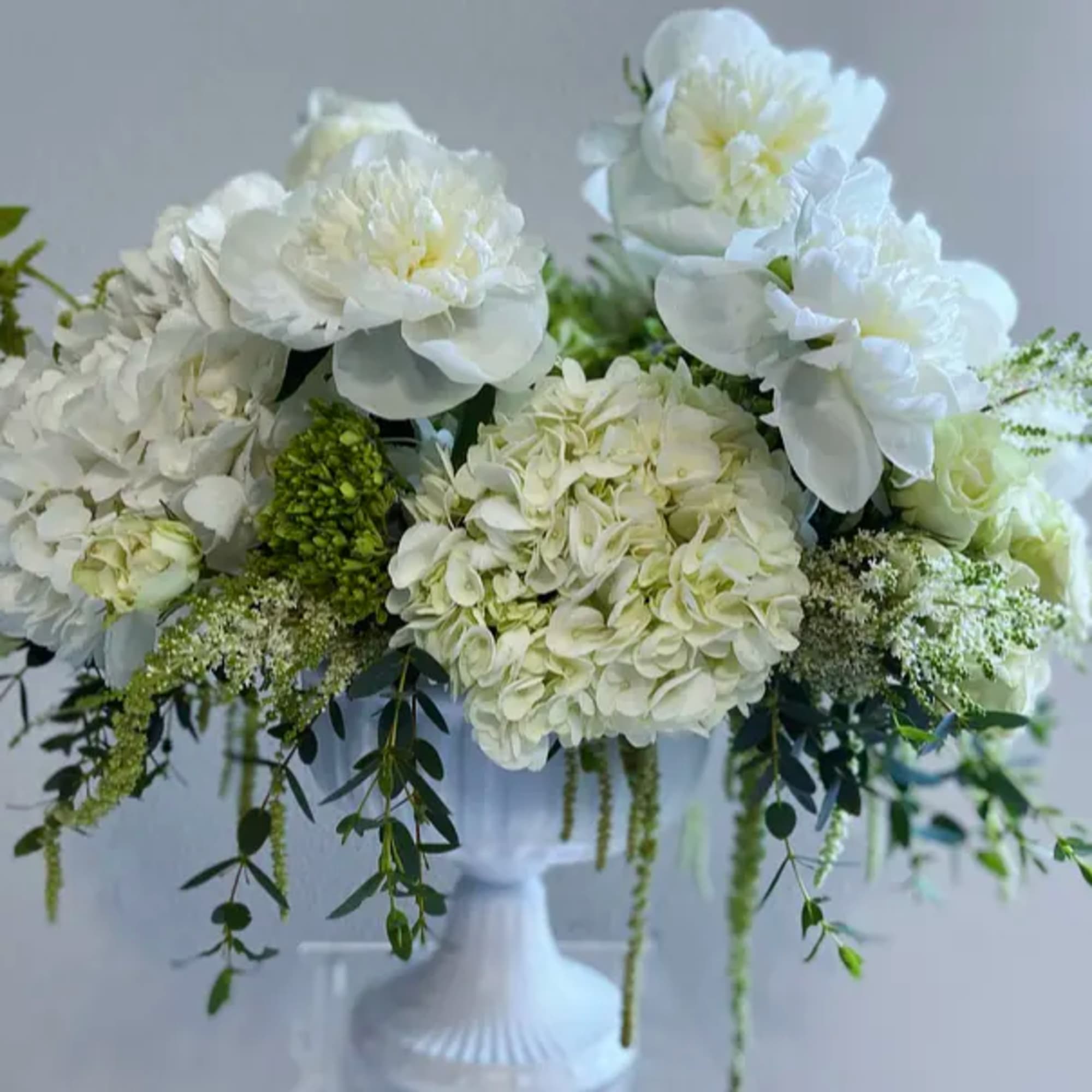 White floral arrangement in a white pedestal vase