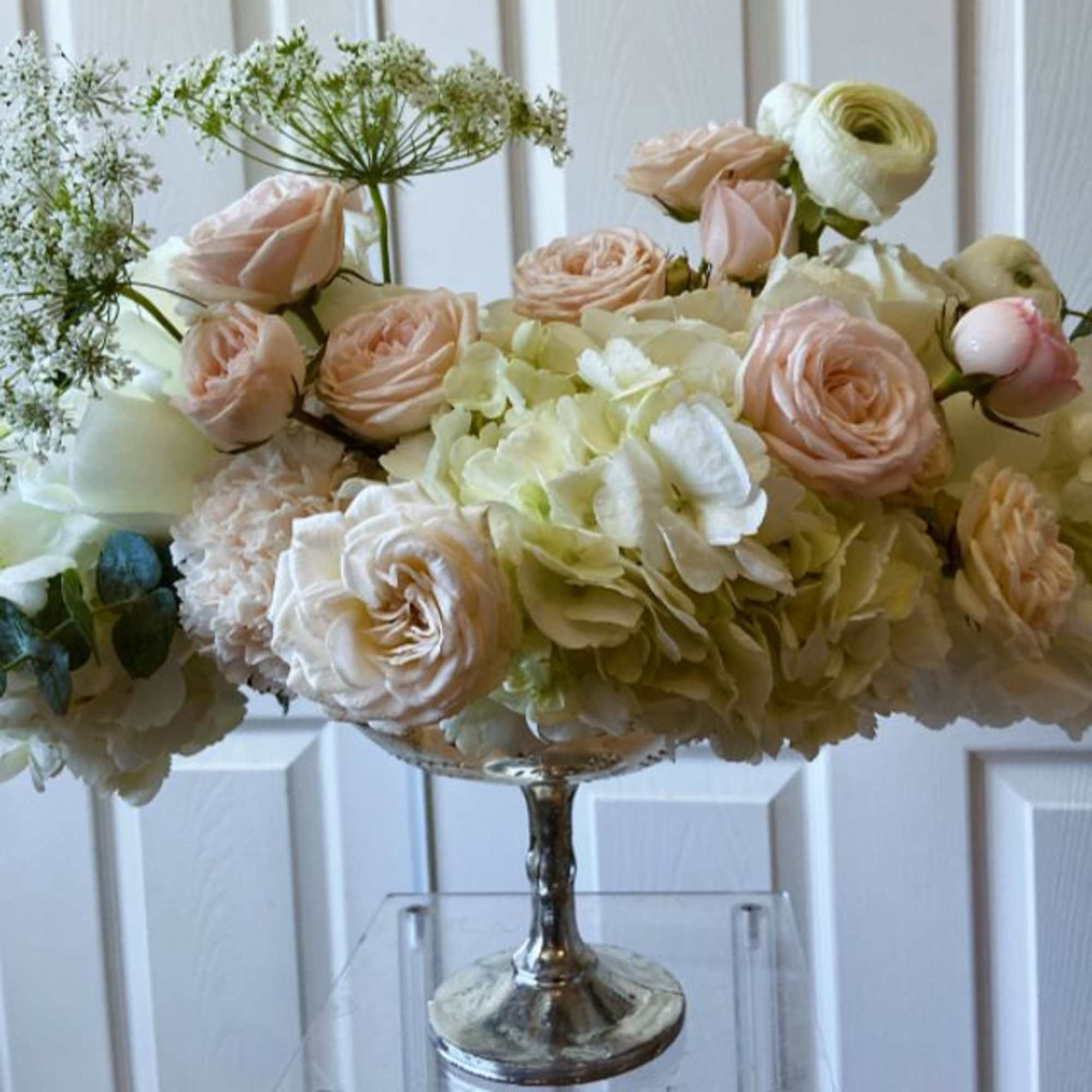 Blush roses and cream hydrangeas in a silver pedestal vase