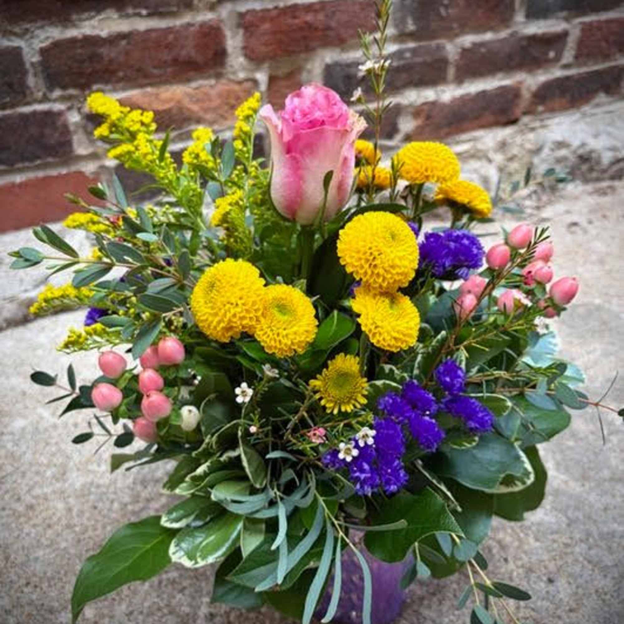A stunning arrangement featuring a white and pink-tipped rose, yellow pomp mums