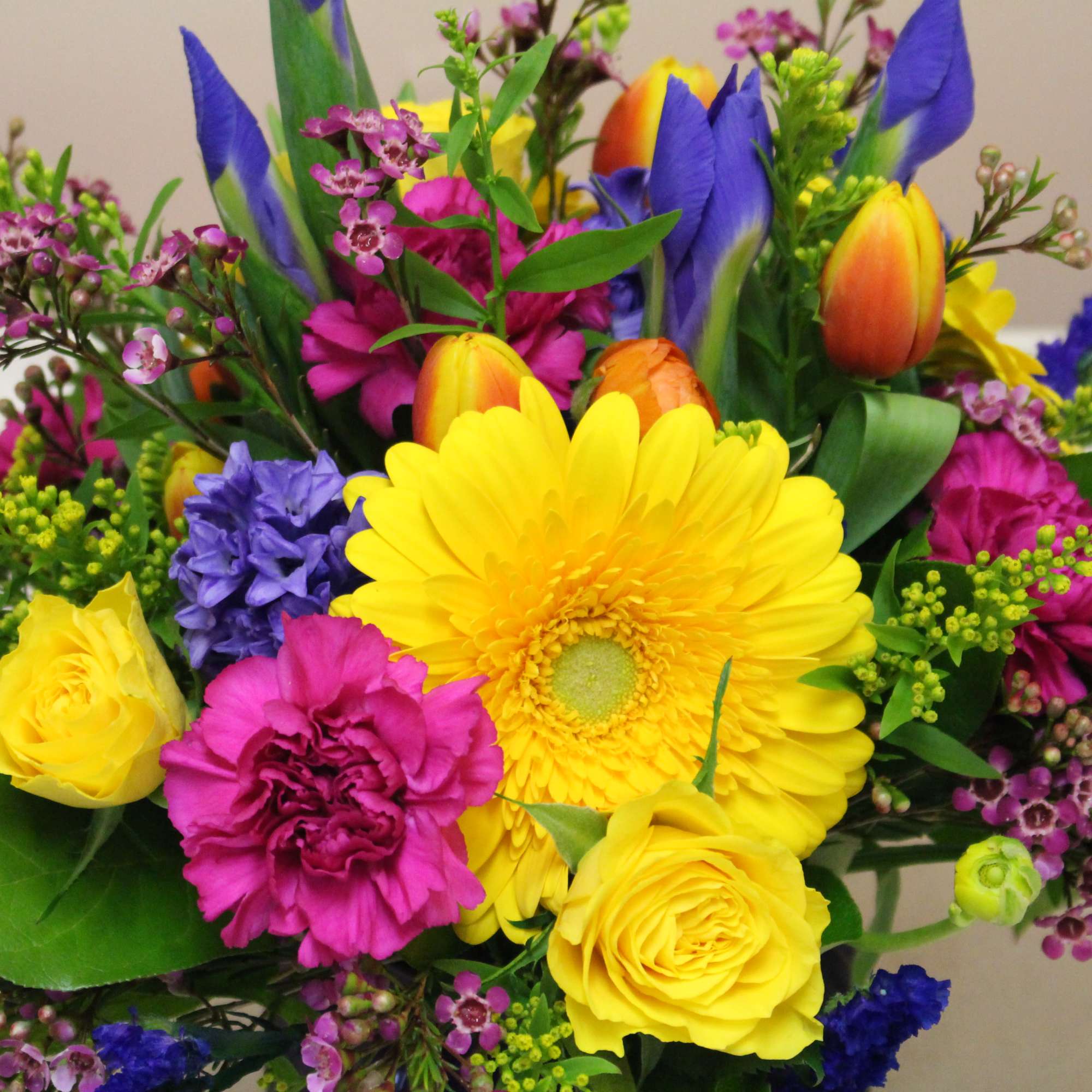 Bright mixed bouquet with yellow gerbera, roses, tulips, and purple blooms