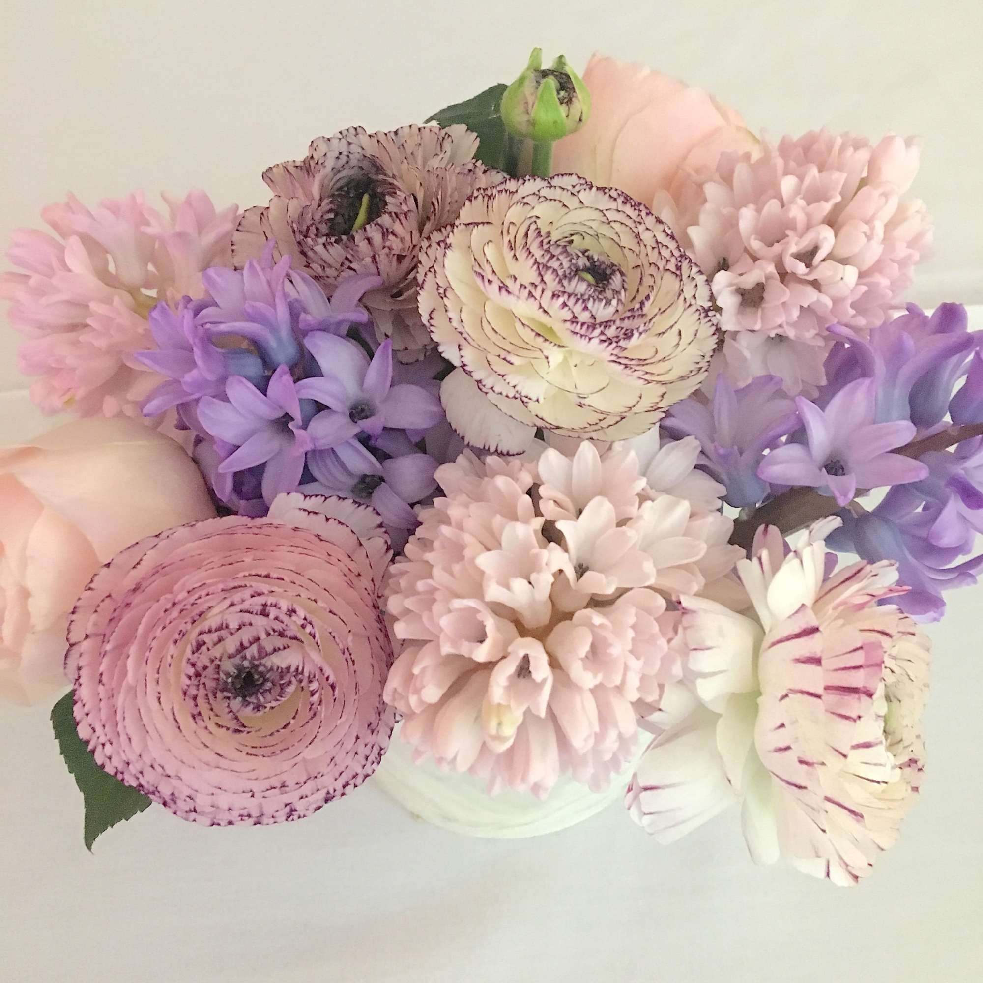 Pastel bouquet of pink, lavender, and cream flowers in a white vase
