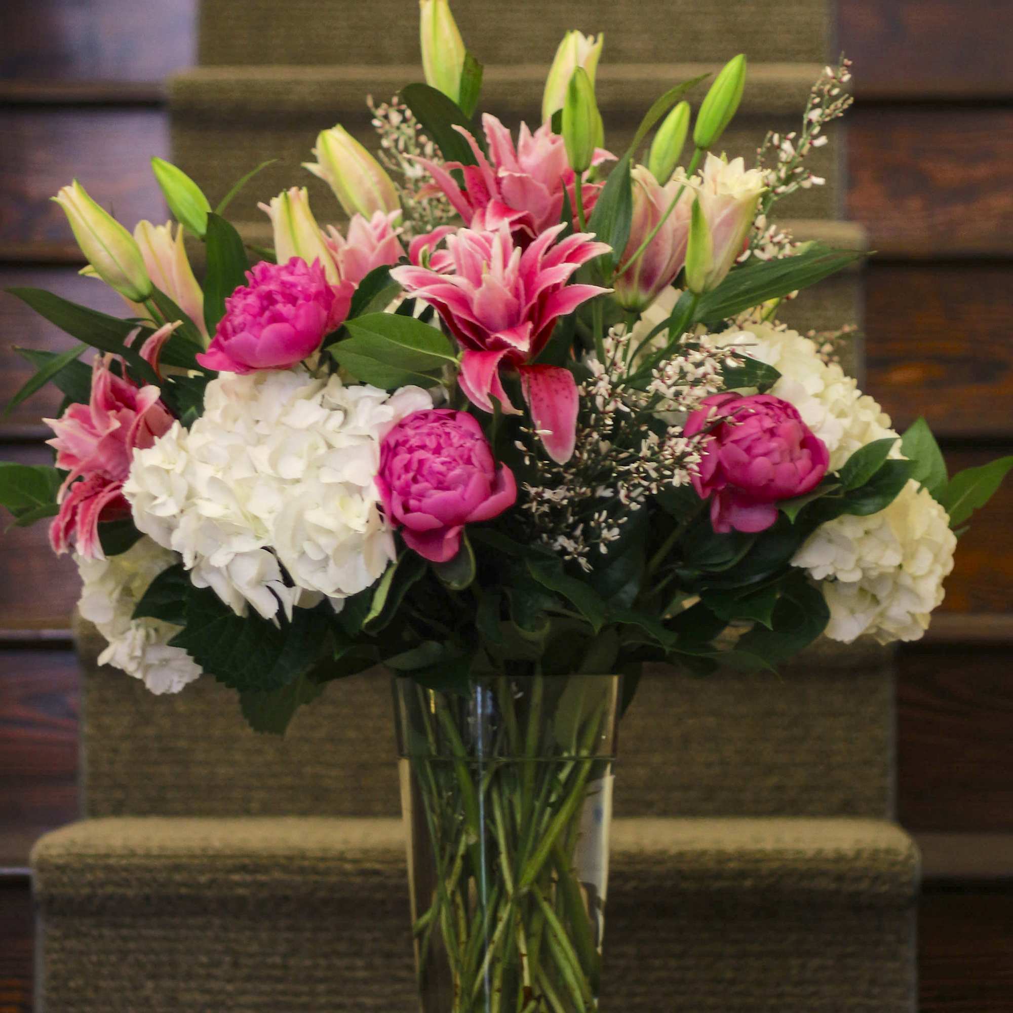 Pink lilies and white hydrangeas in a clear glass vase