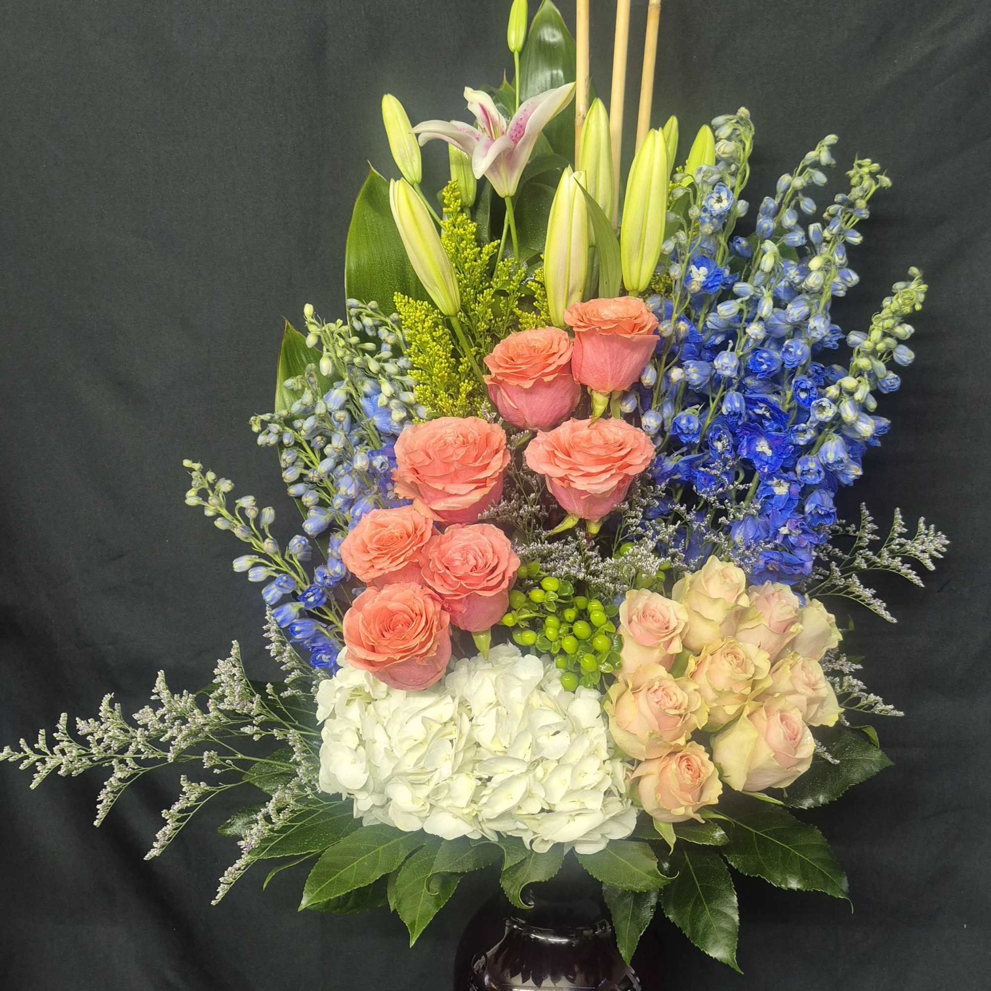 A TALL AN ELEGANT DESIGN FEATURING PINK STARGAZER LILLIES, BLUE DELPHINIUMS, GREEN