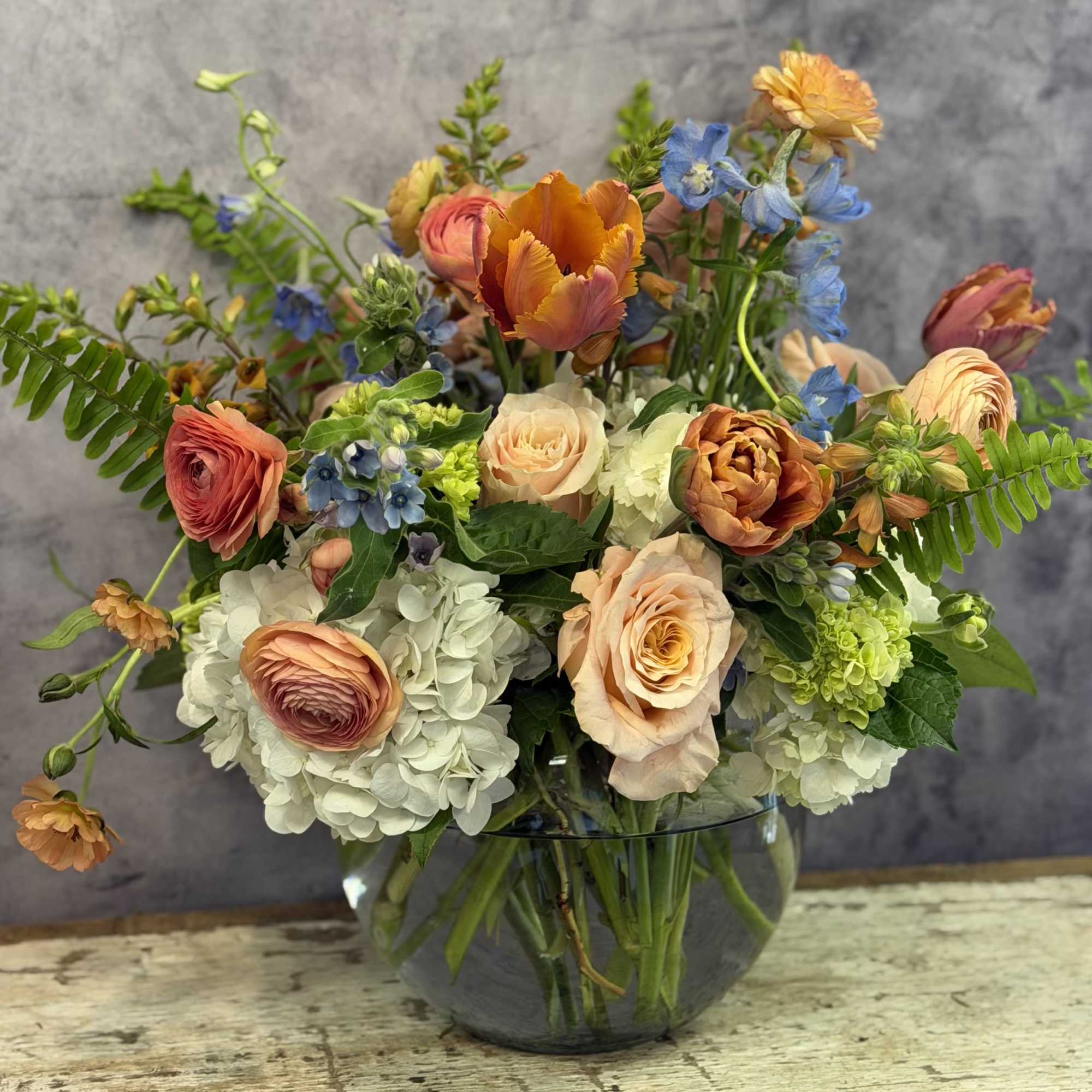 Peach and orange roses paired with soft blush ranunculus and a sprinkling