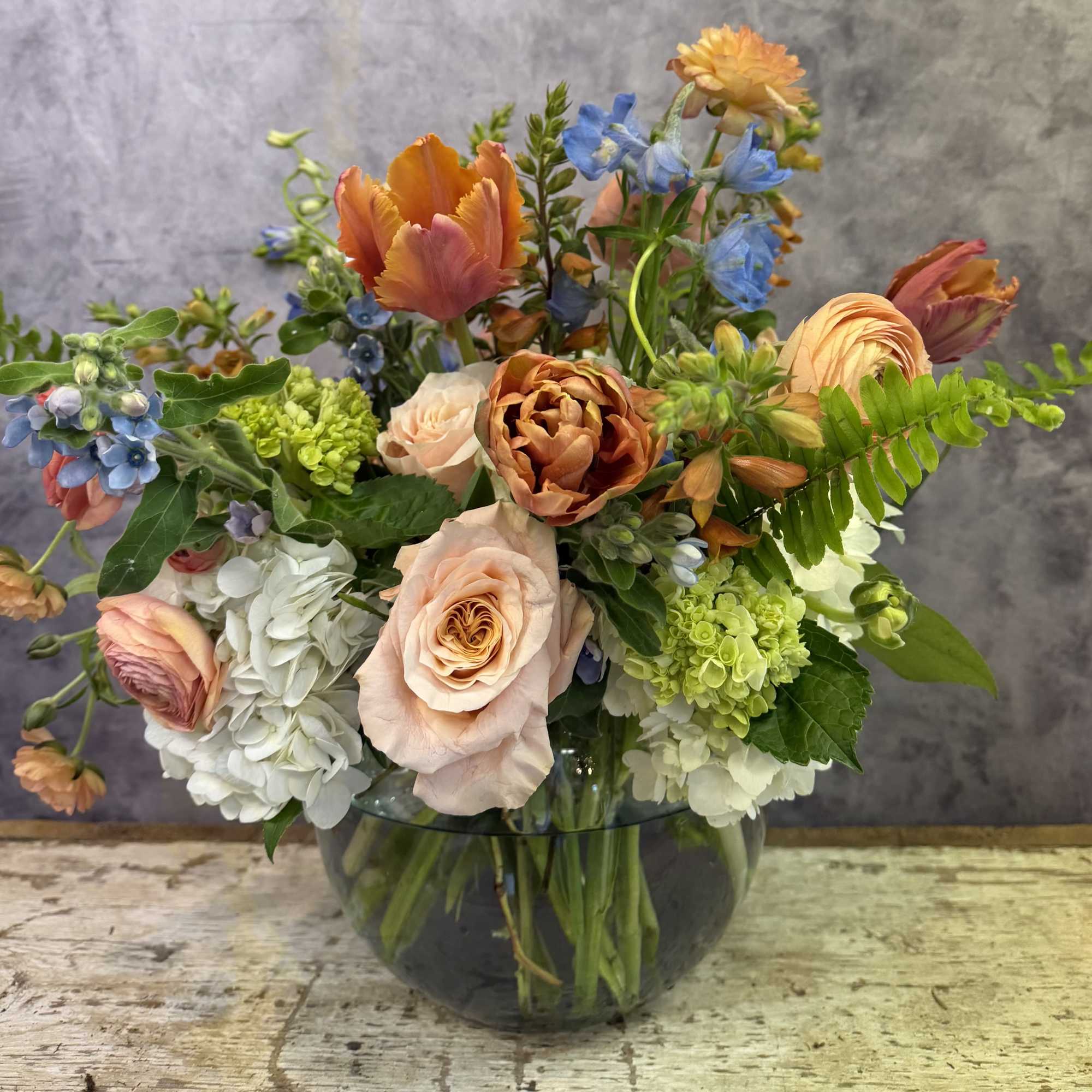 Peach and orange roses paired with soft blush ranunculus and a sprinkling