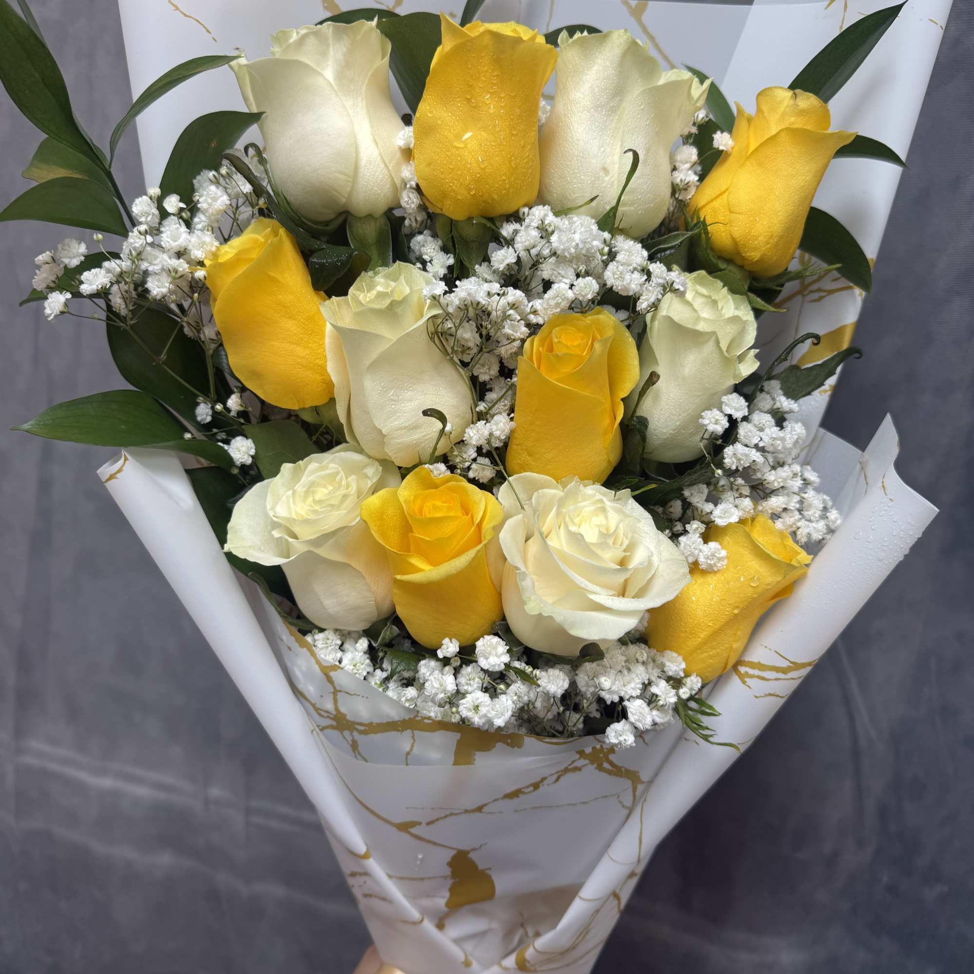 
Bright yellow and soft white roses with green foliage, beautifully wrapped in