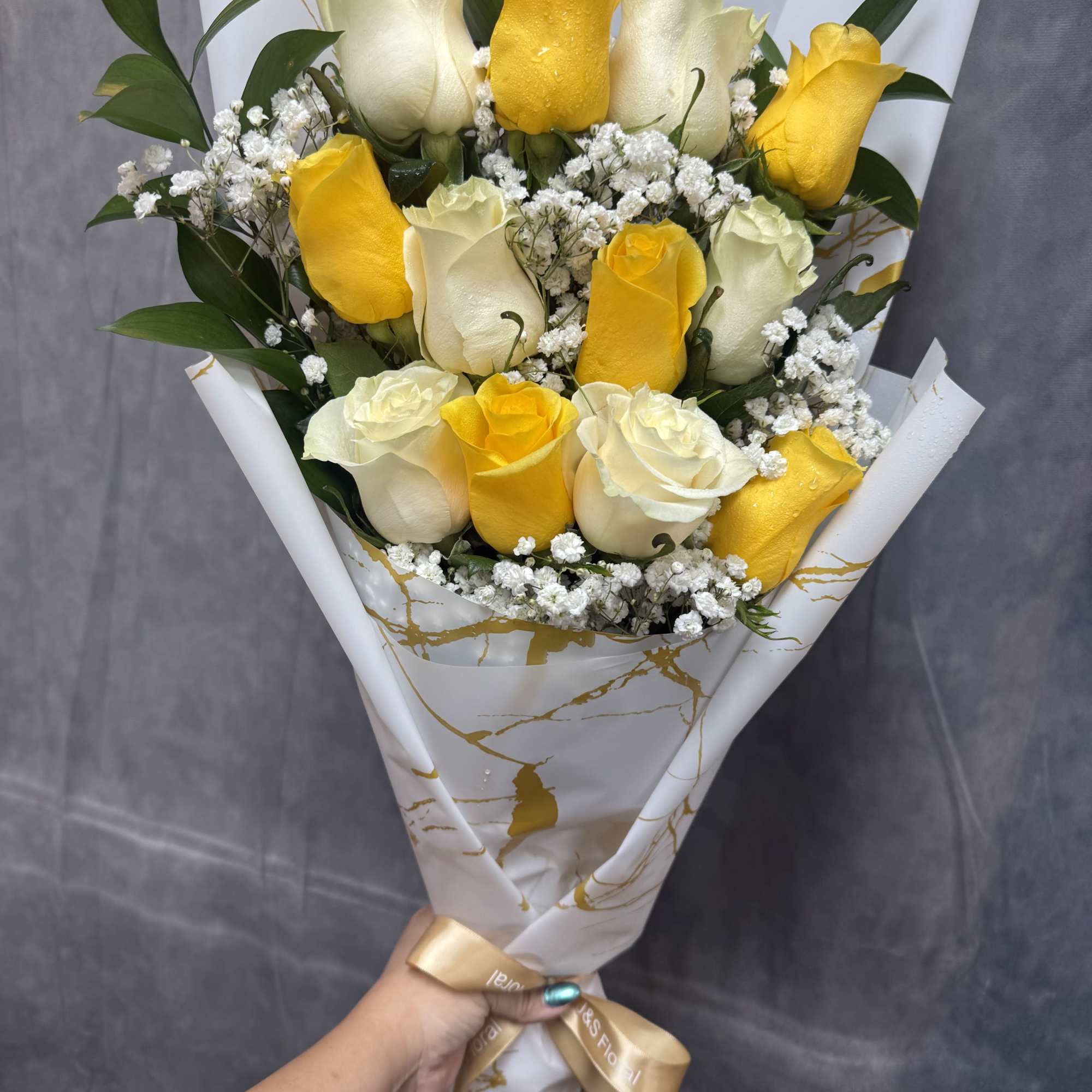 
Bright yellow and soft white roses with green foliage, beautifully wrapped in