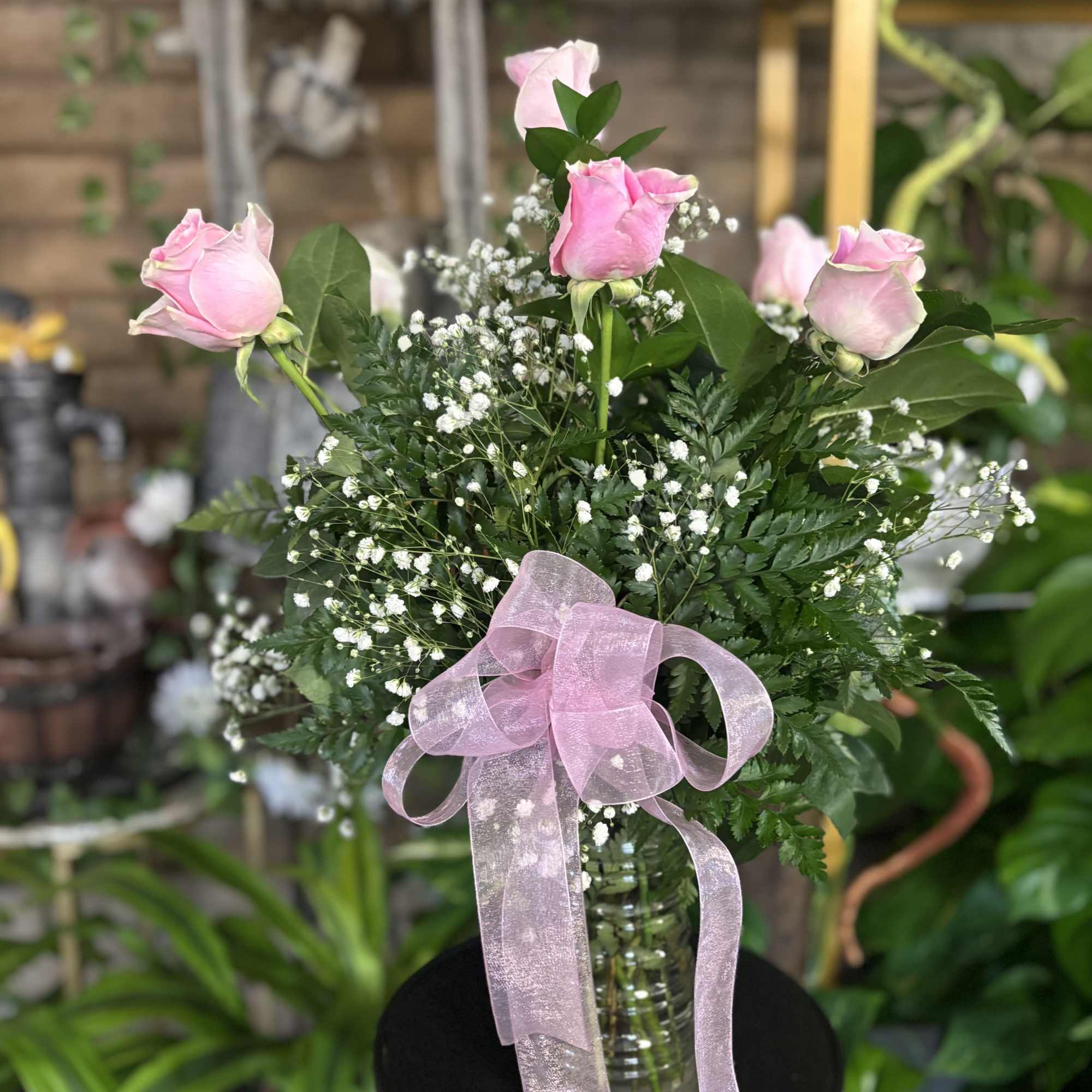 Pink roses in a glass vase with a pink ribbon
