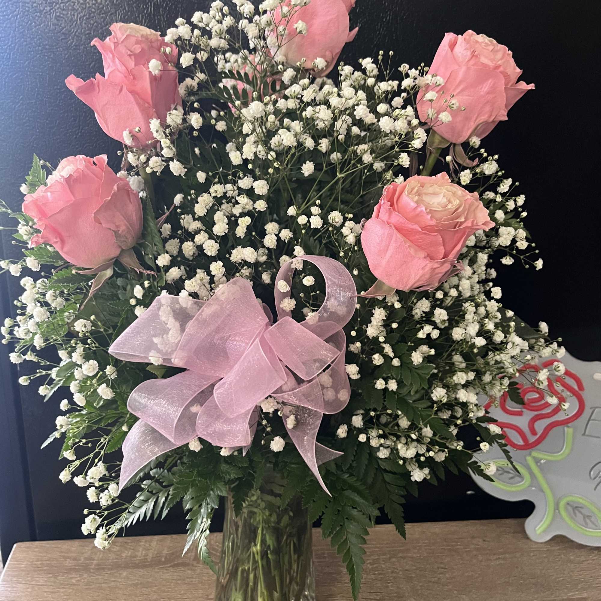 Pink roses with baby's breath in a glass vase and pink ribbon