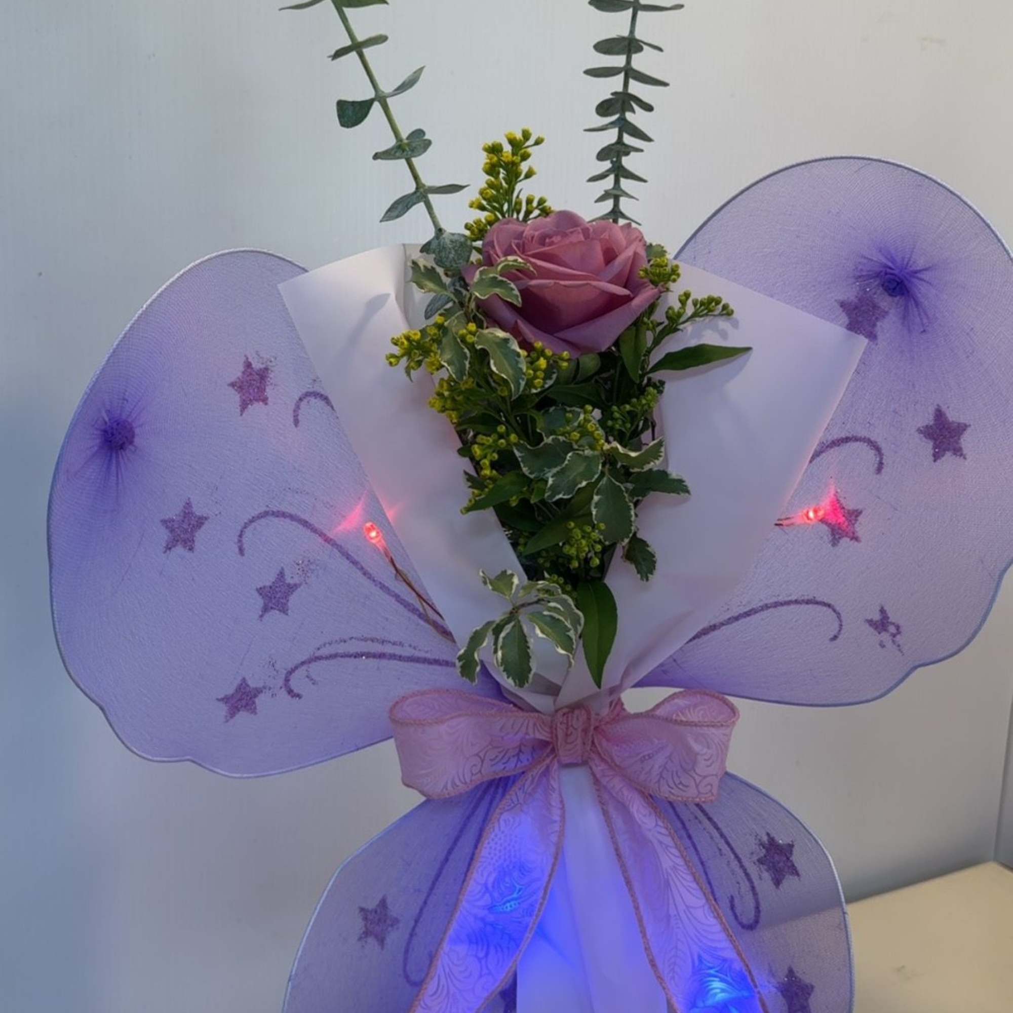 A rose or Gerber accented with fresh greenery, filler, and sparkling butterfly