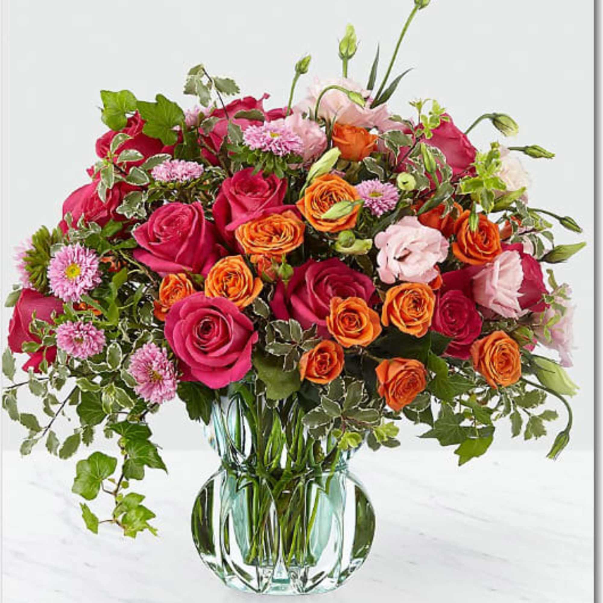 Mixed pink and orange roses in a clear glass vase