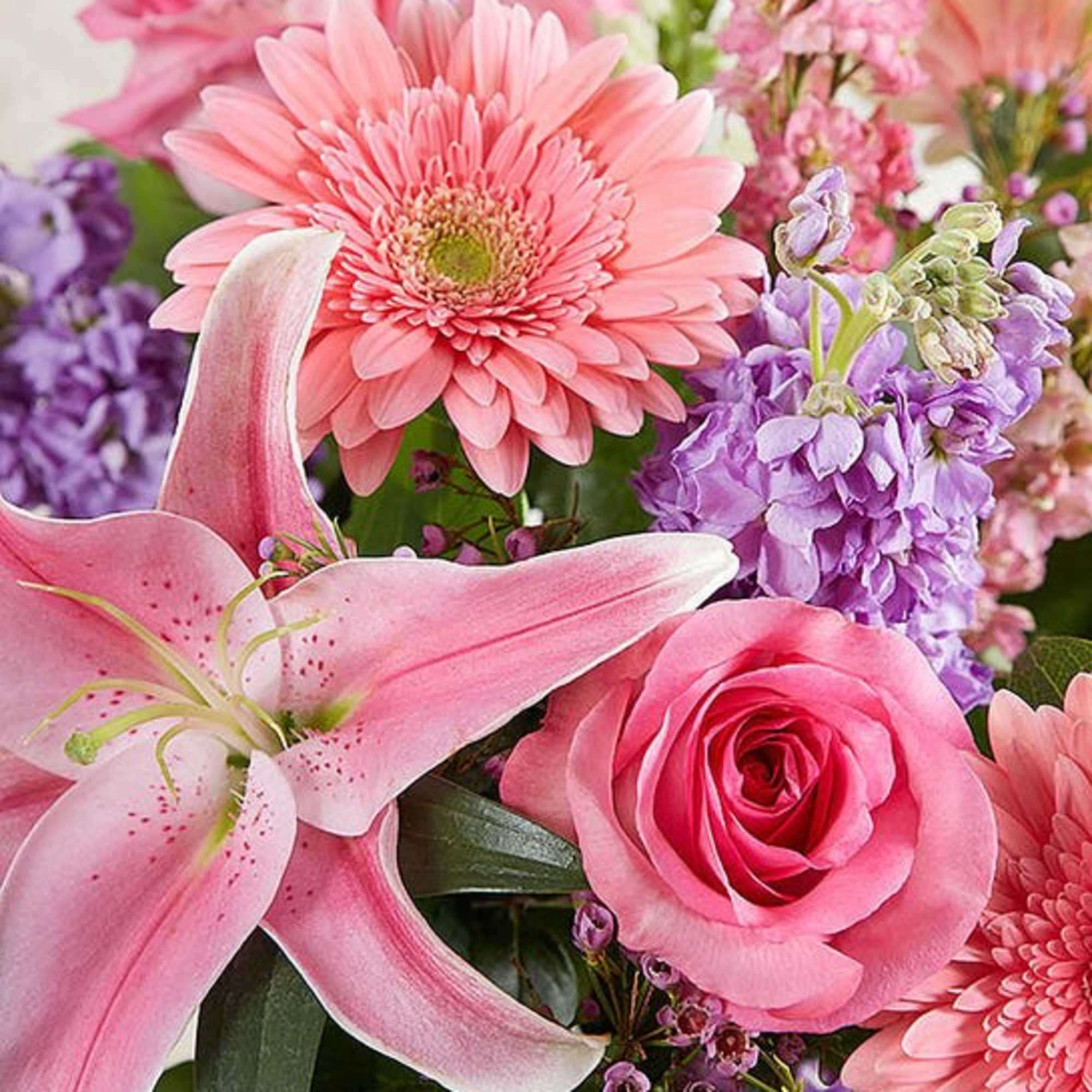 Pink lilies, roses, and gerbera daisies in a mixed bouquet