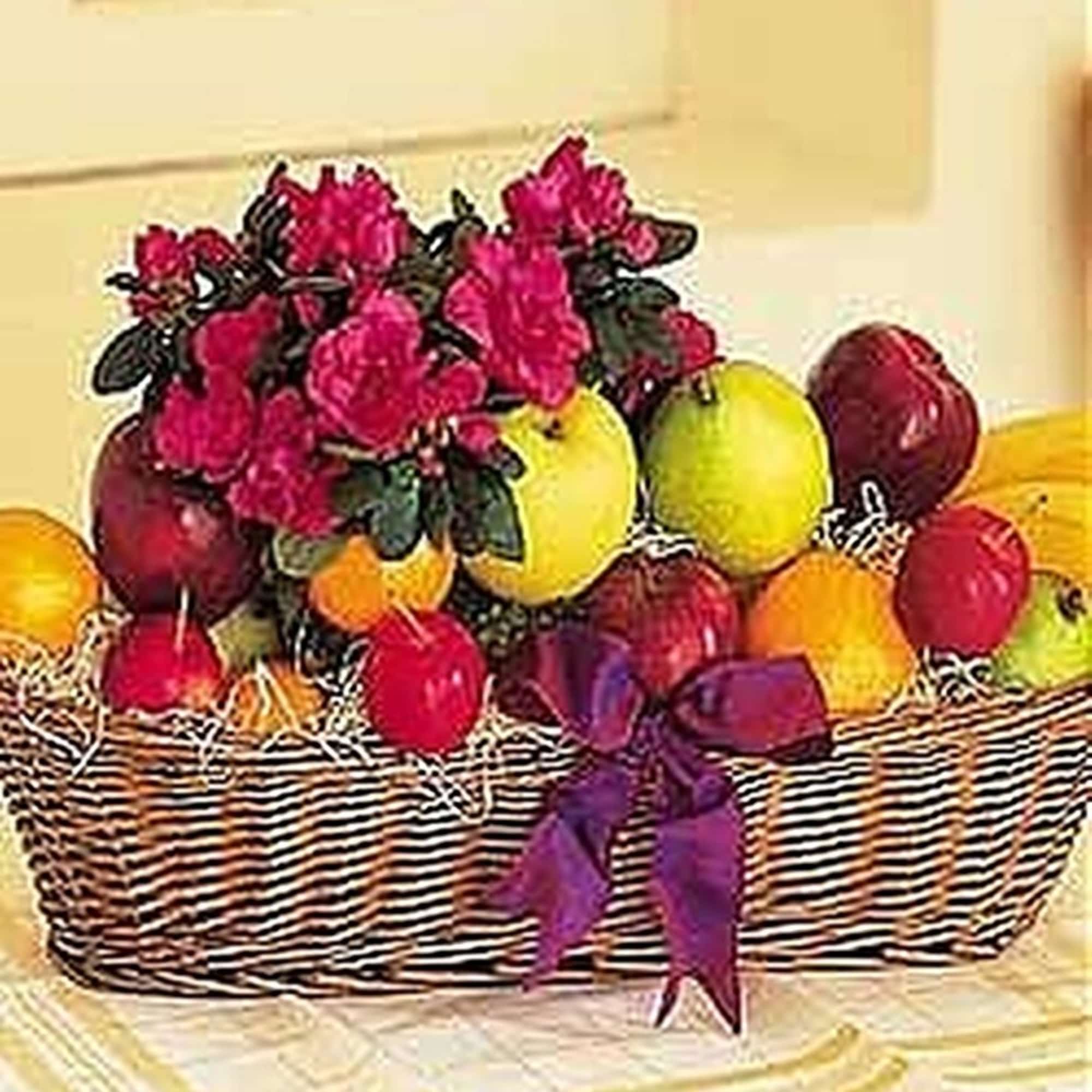 Wicker basket filled with assorted fruit and a pink flowering plant, tied with a purple bow