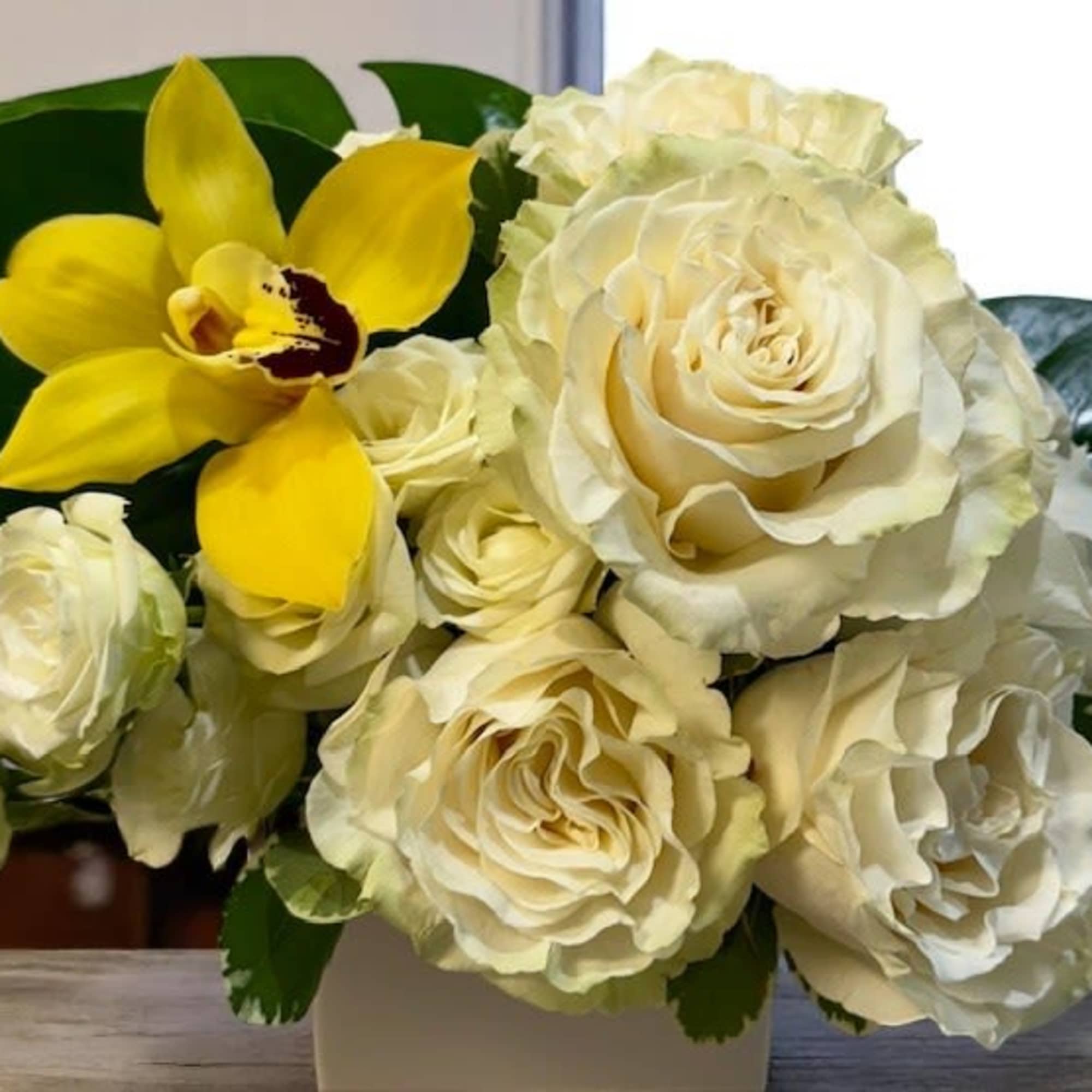Cream roses and a yellow orchid in a white vase